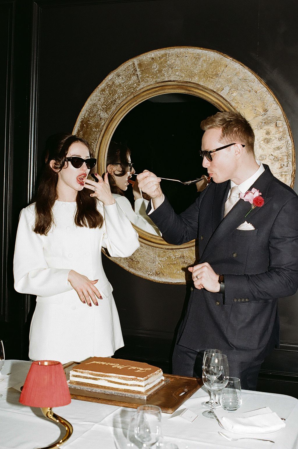A sequence of photos shows two people playfully engaging in a cake smashing moment at a formal dinner setting.