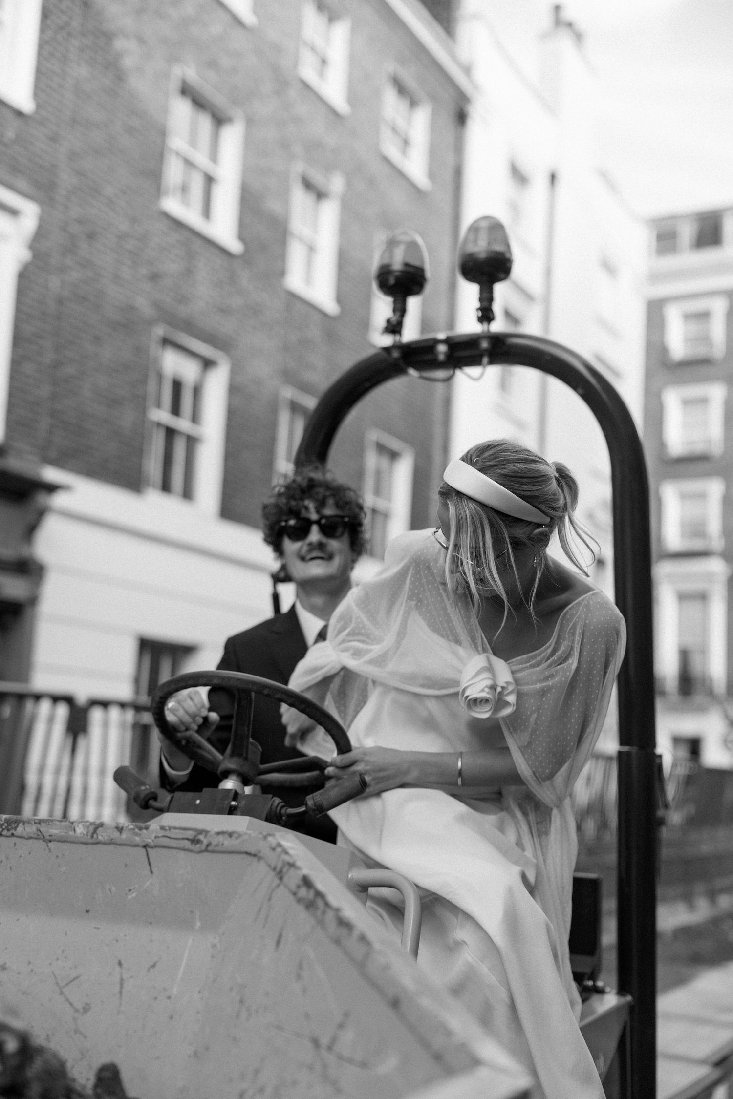Black and white photo of newlyweds sitting in a yellow construction vehicle.