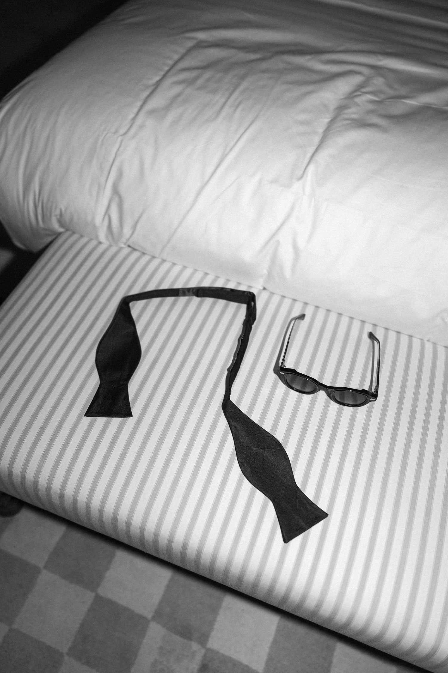 Two bow ties and sunglasses arranged neatly on a striped surface as wedding day accessories.