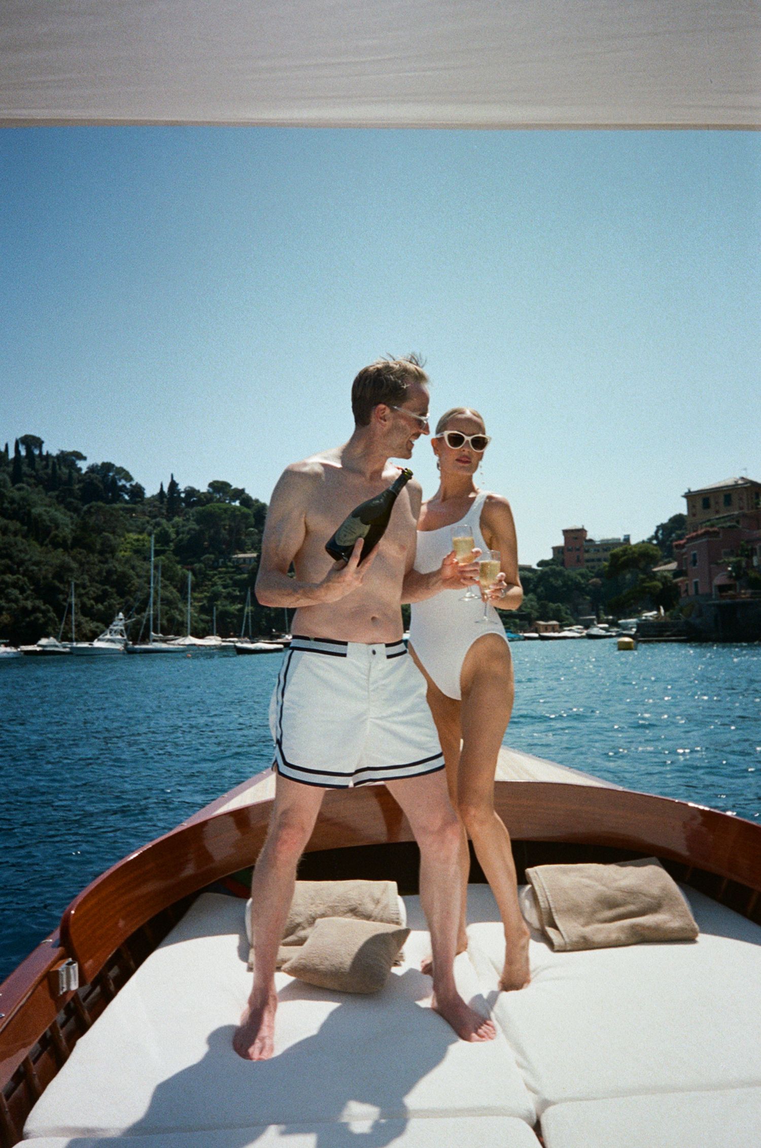 Couple enjoying champagne on a luxury boat in Portofino, Italy, on a sunny day.