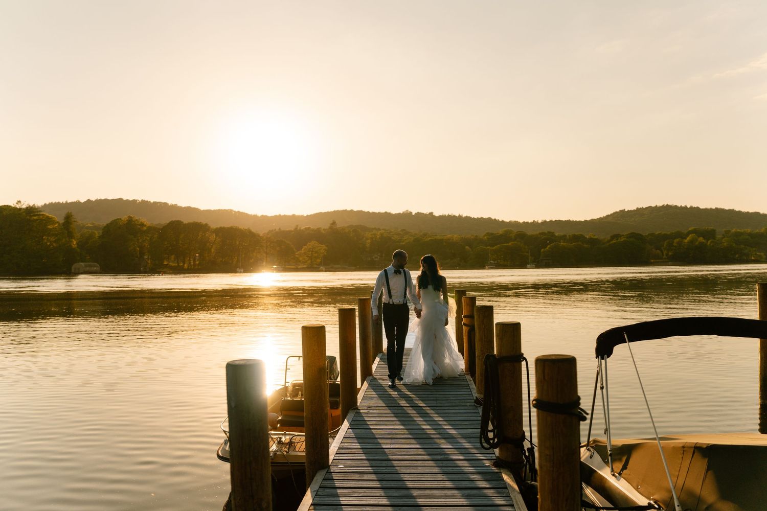 Scenic wooden dock extending into calm waters at sunset with mountains in the distance.