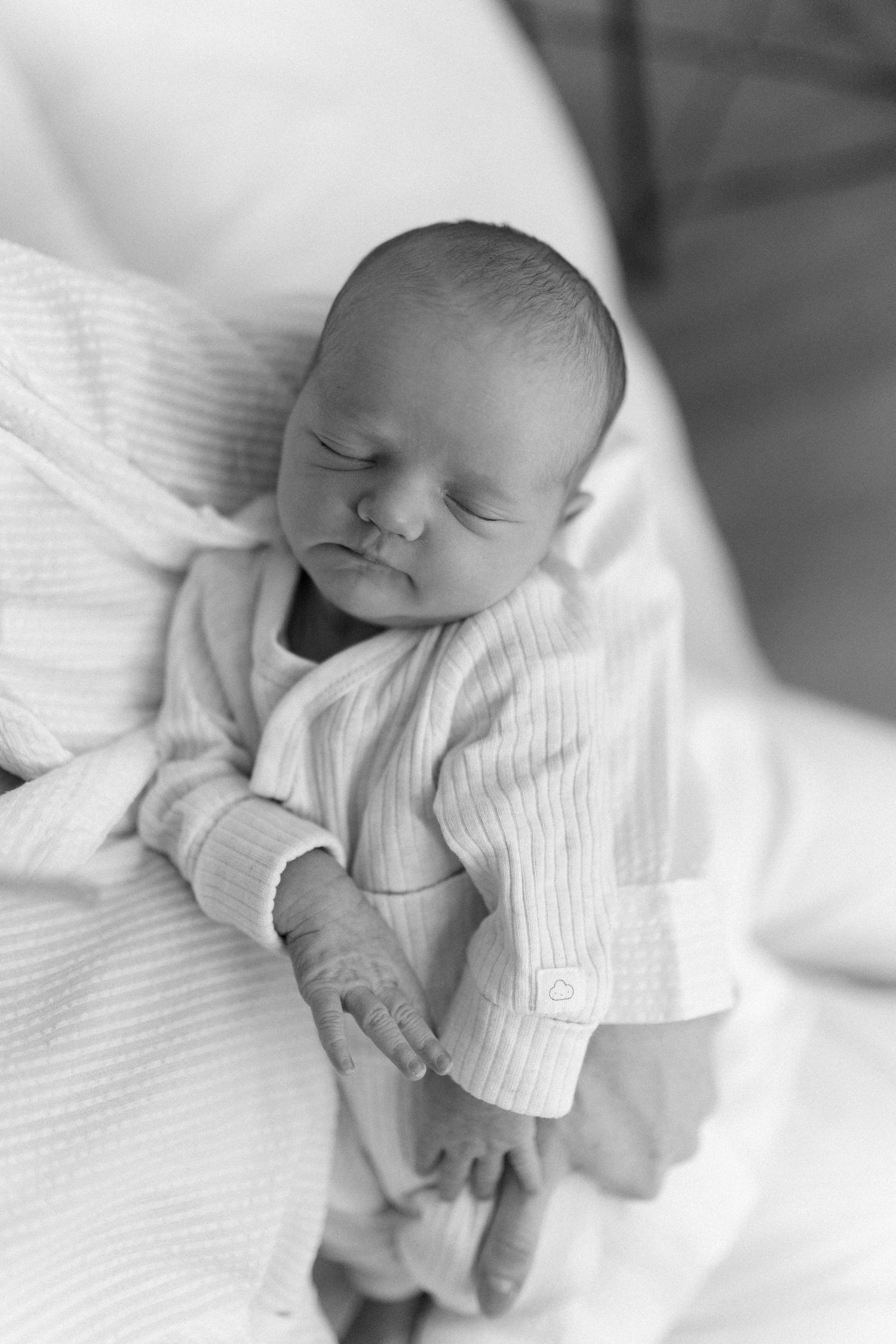 Peaceful black and white portraits of a sleeping infant in soft white clothing.