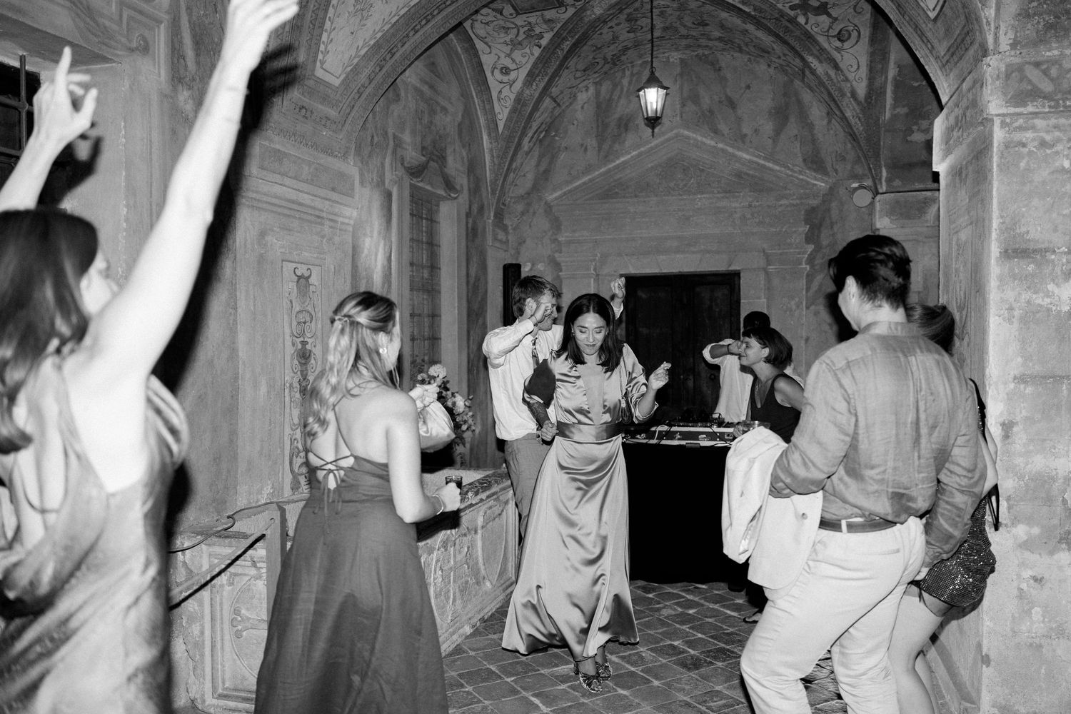 People dancing and celebrating in a historic venue with classical architecture and lighting.