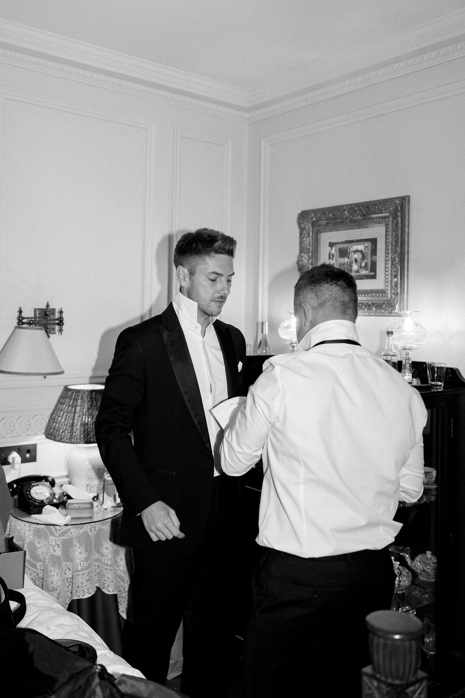 Two people in formalwear adjust their attire before an event.