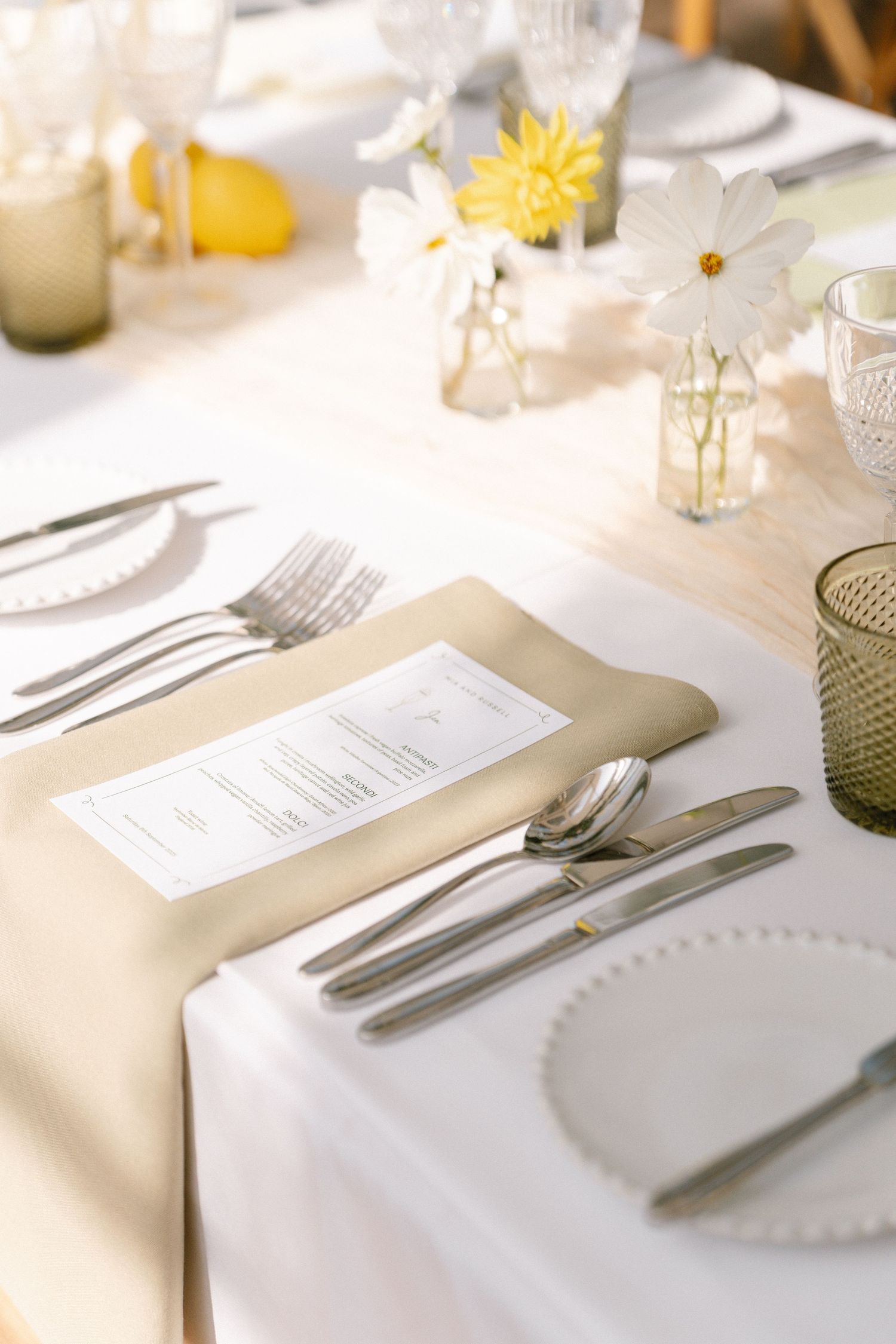 Place settings with white linens, silverware, and menu cards on an elegant dining table.