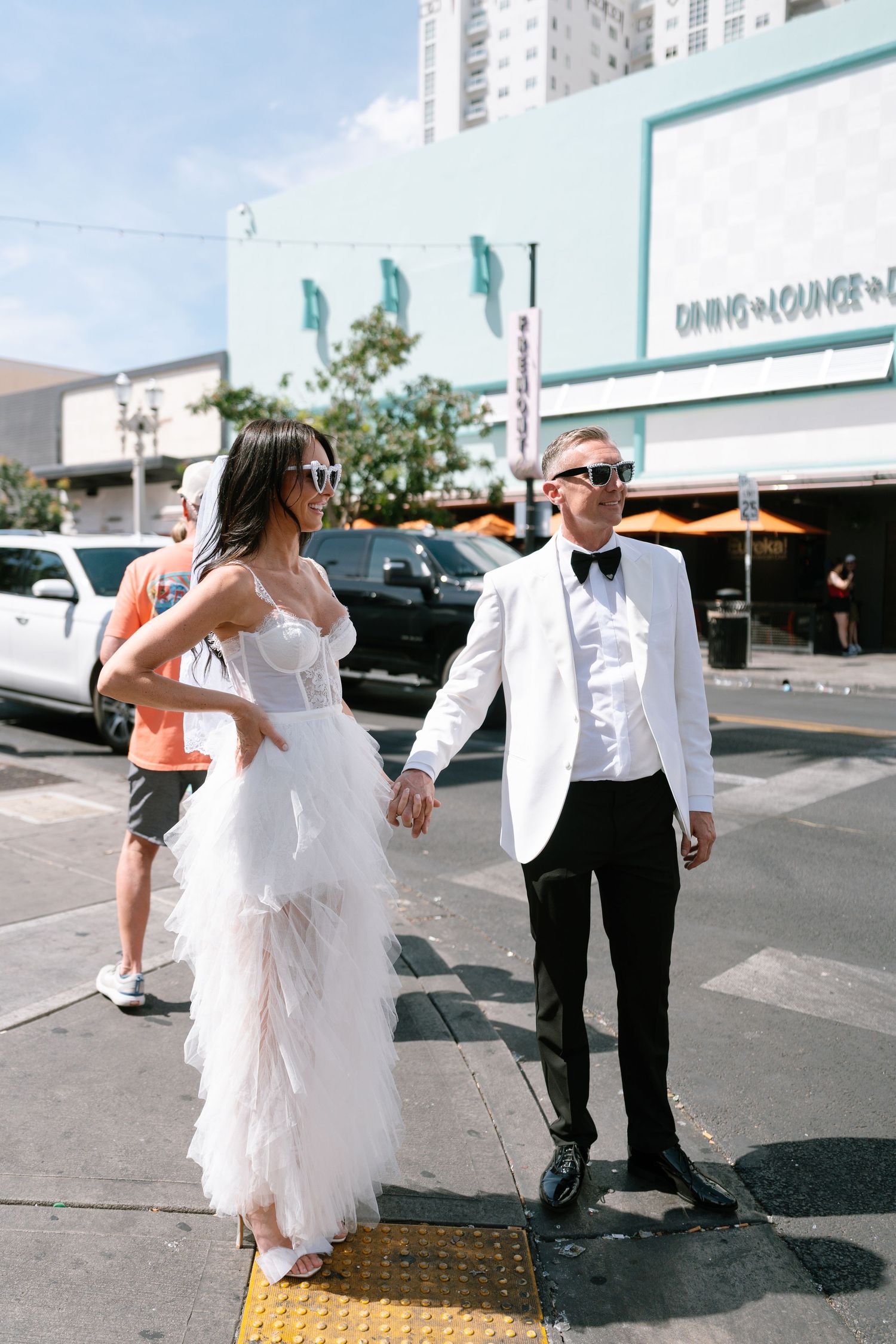 Wedding couple crossing street in downtown area with vintage buildings.