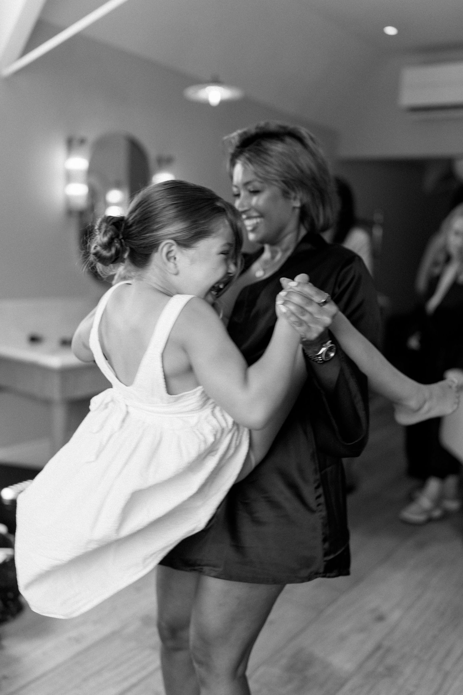 Black and white photo of two women dancing together at an indoor celebration.