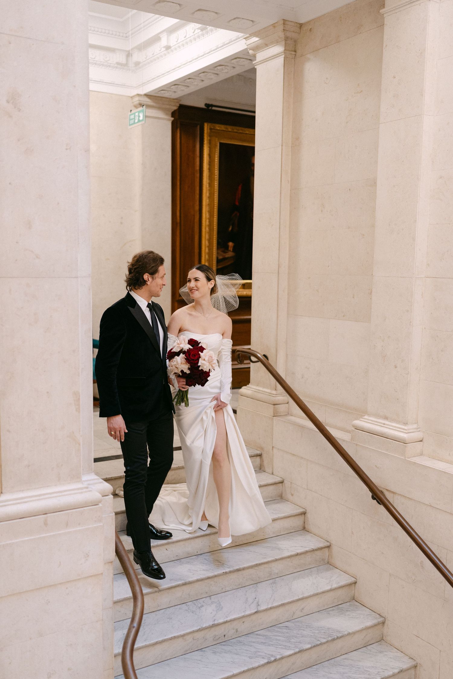 A couple shares an intimate moment on an elegant marble staircase during their wedding day.