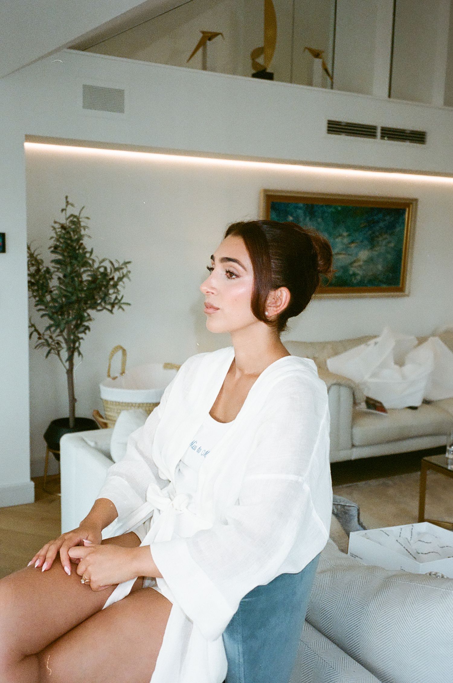 A person in a white robe lounges on a modern couch in a bright, minimalist living room.