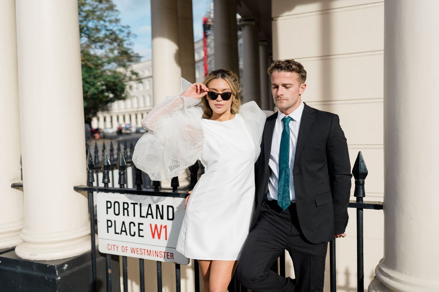 A couple poses near elegant white columns at Portland Place in London.