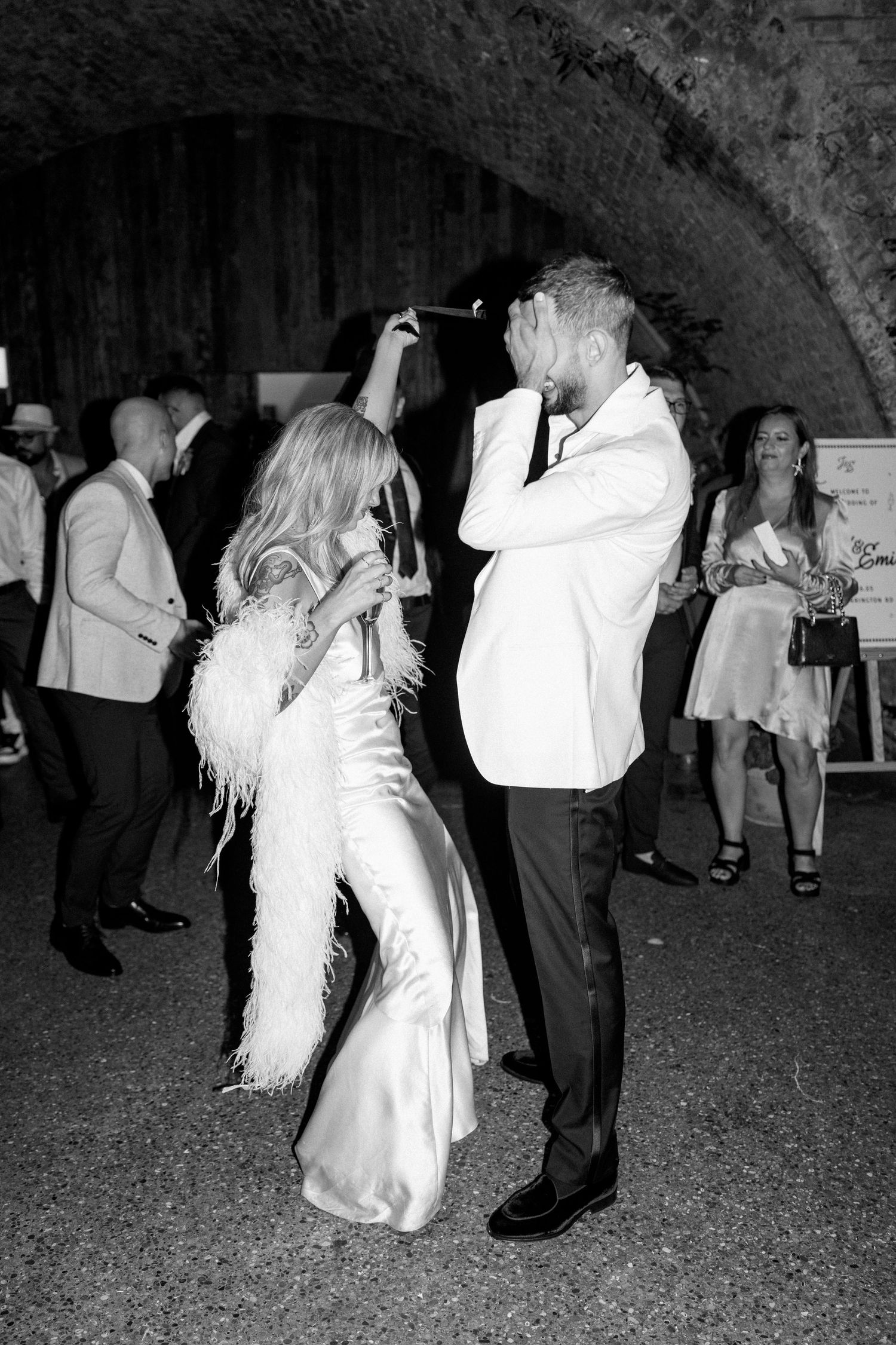 A couple dances together at their wedding reception under string lights.