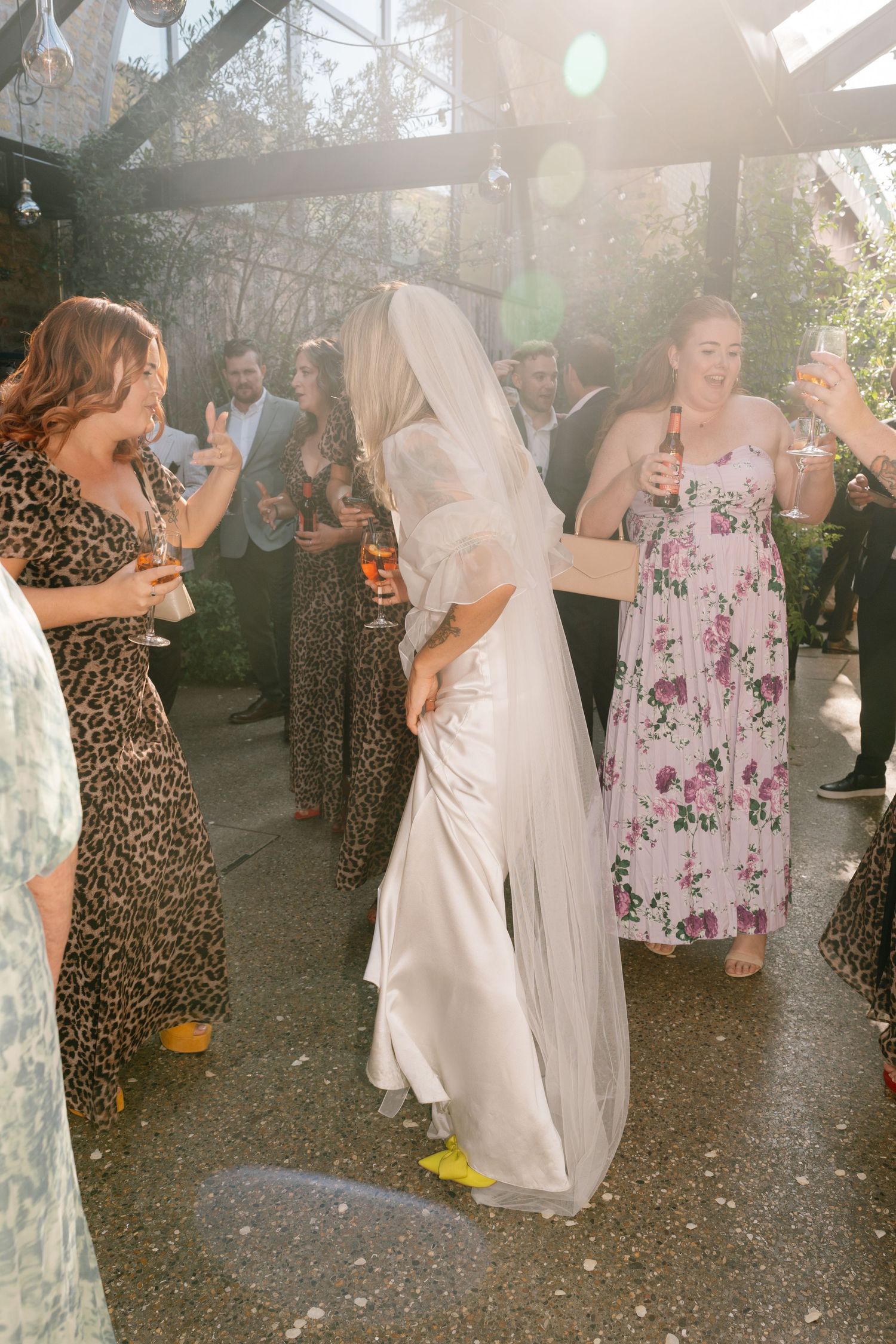 Wedding guests dance and celebrate on an outdoor patio under twinkling lights and evening sky.