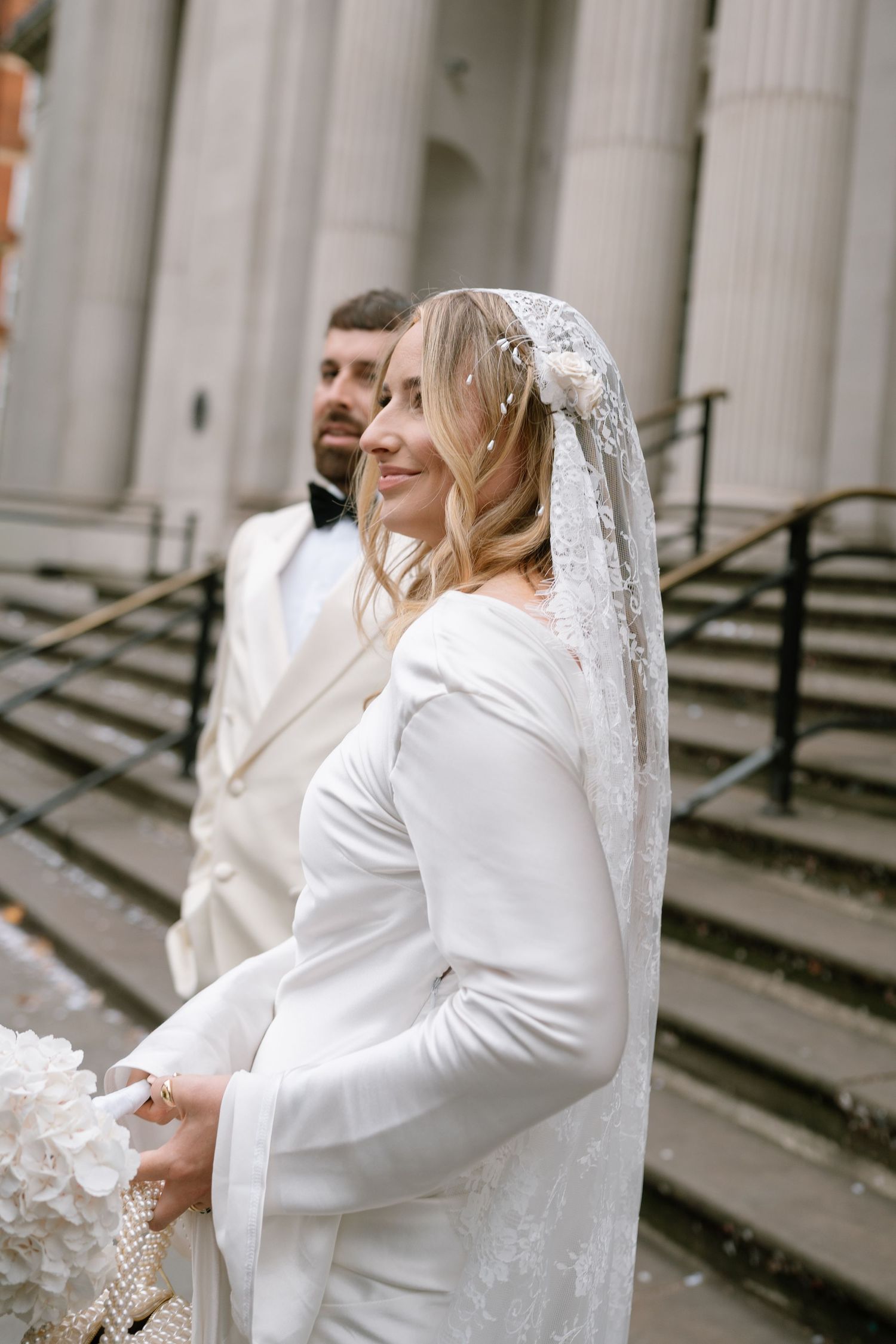 Wedding couple sharing intimate moment by white classical columns.
