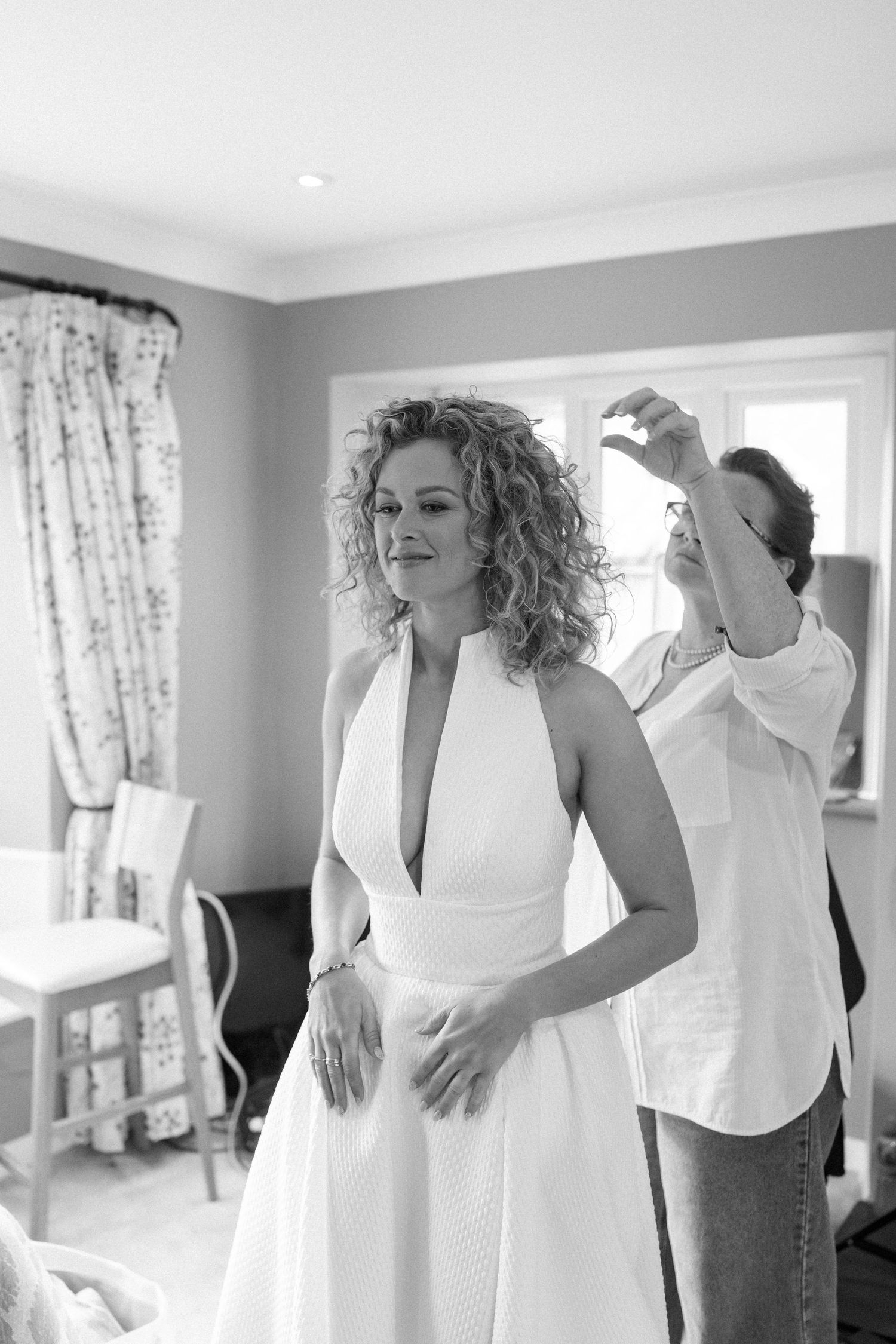 A series of black and white photos capturing joyful moments during wedding preparations in a bright room.