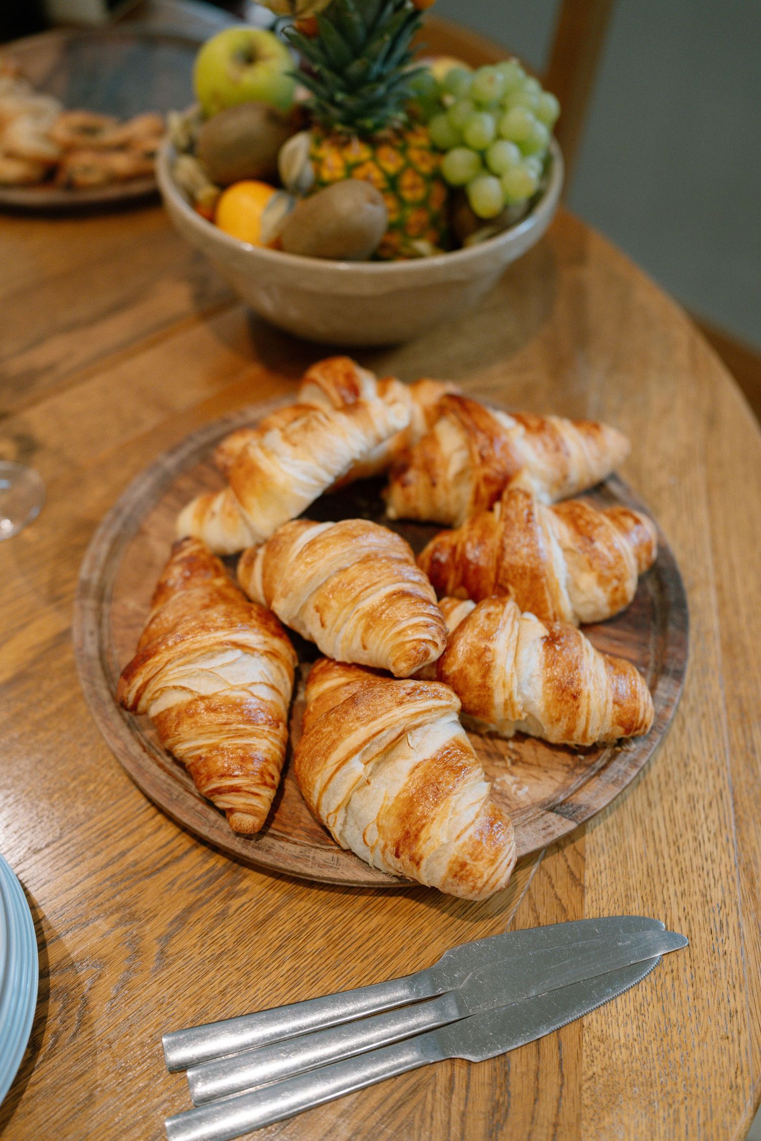 Fresh golden croissants arranged on a rustic wooden serving board.