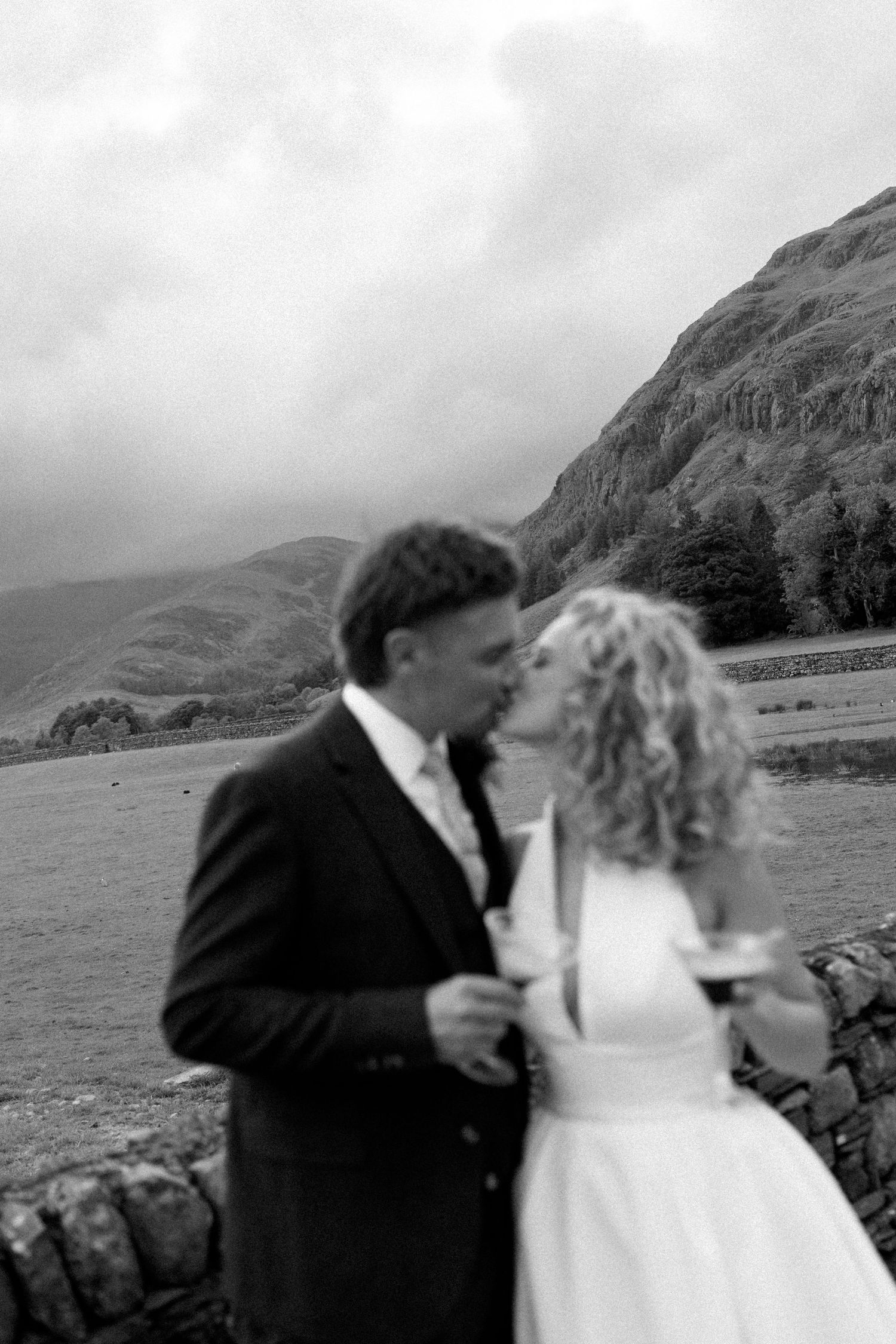 Black and white wedding portrait with dramatic mountain landscape backdrop.