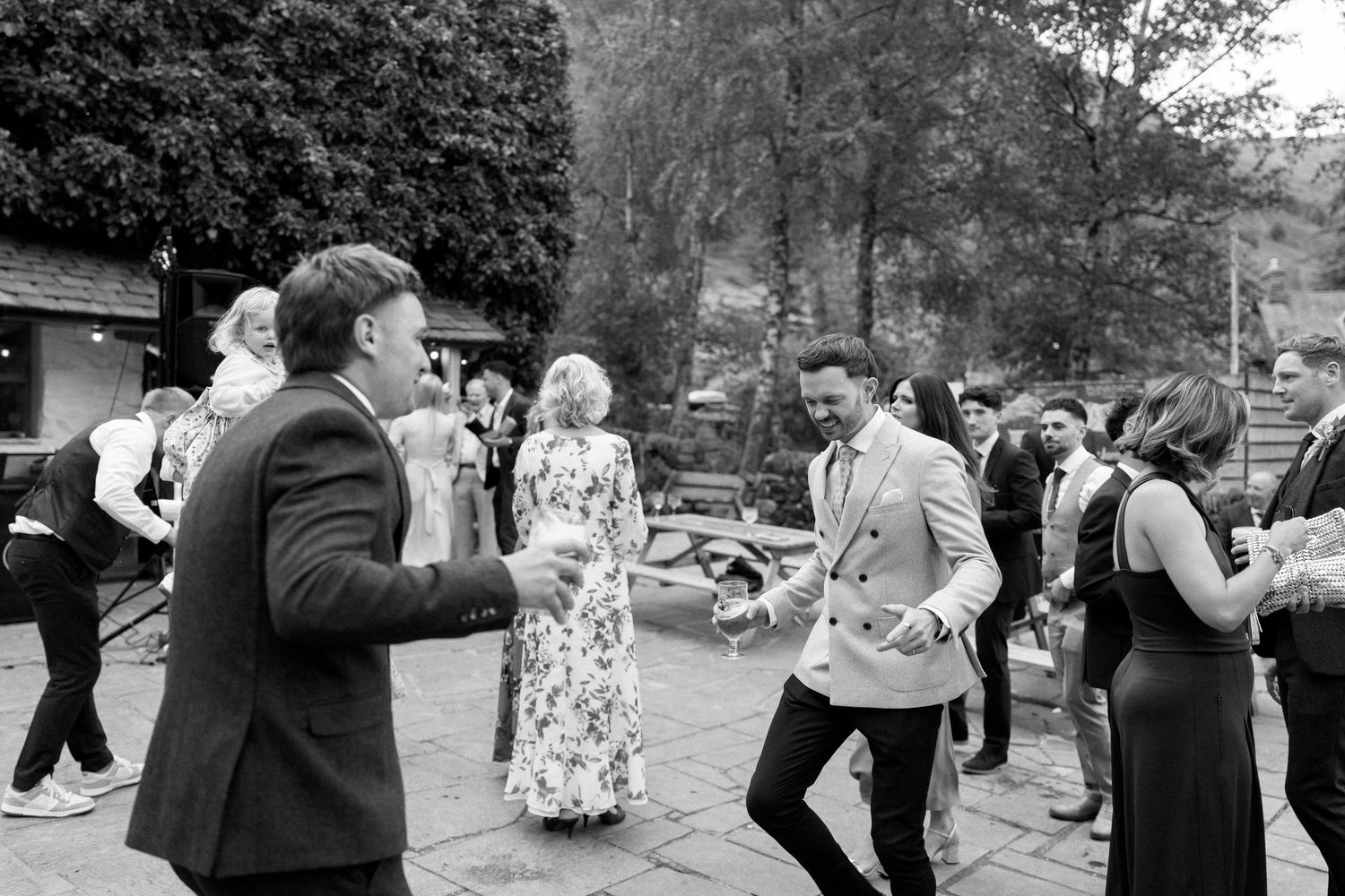 Wedding guests mingling and dancing outdoors at reception.