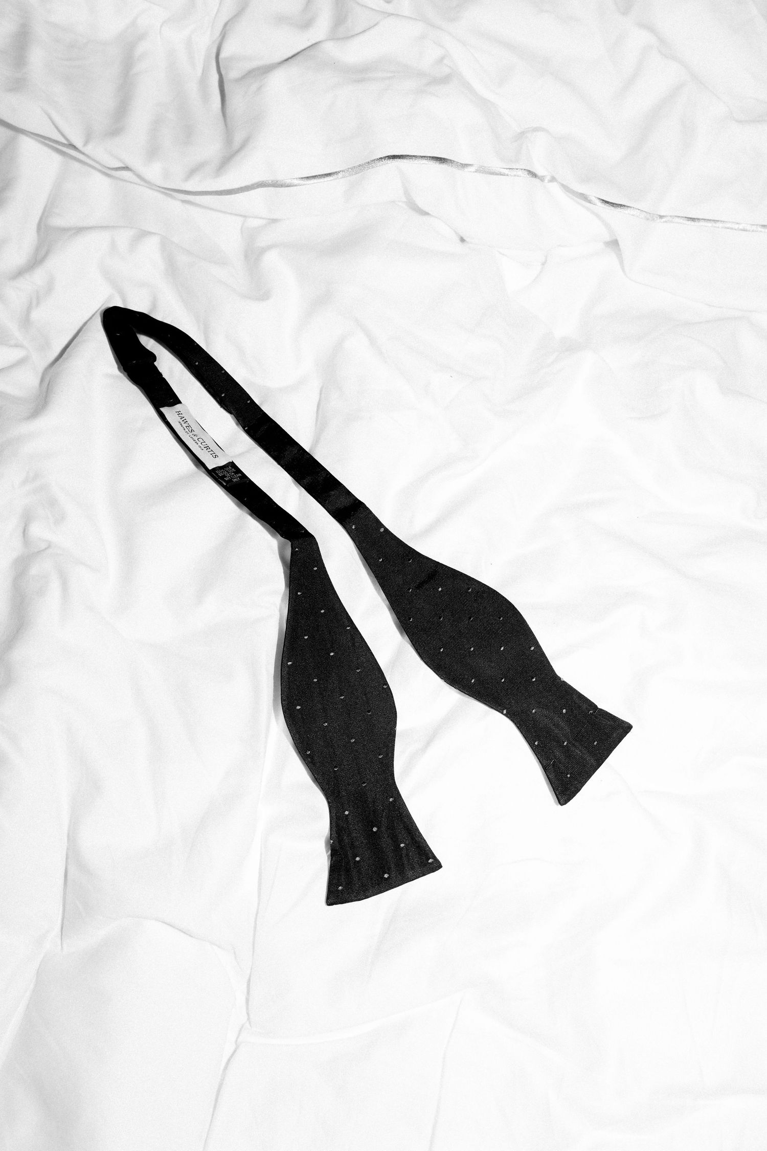 Black bow ties arranged on white crumpled paper in minimalist composition.