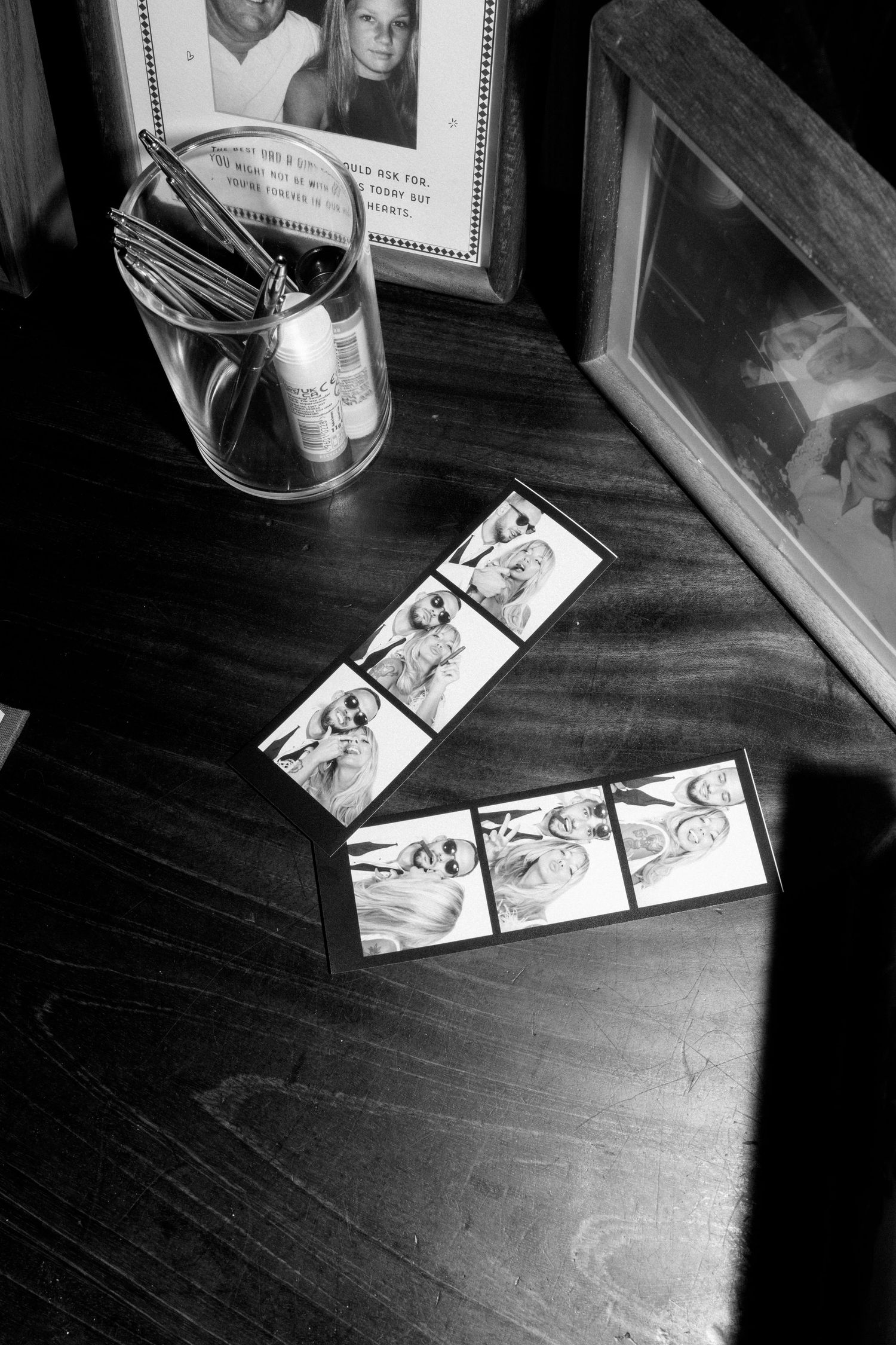 Black and white photo strips arranged on a dark wooden surface.