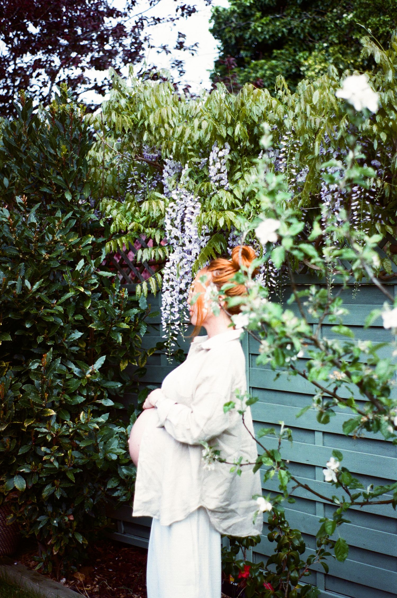 A series of images showing a person in a white dress standing near green foliage and a blue wall in a garden setting.