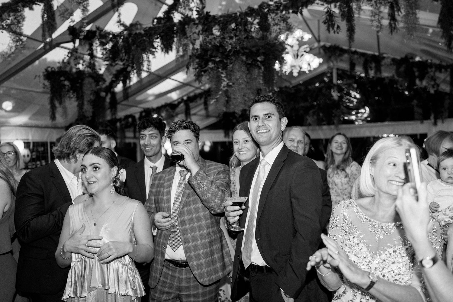Wedding reception guests mingling under decorated ceiling in black and white.