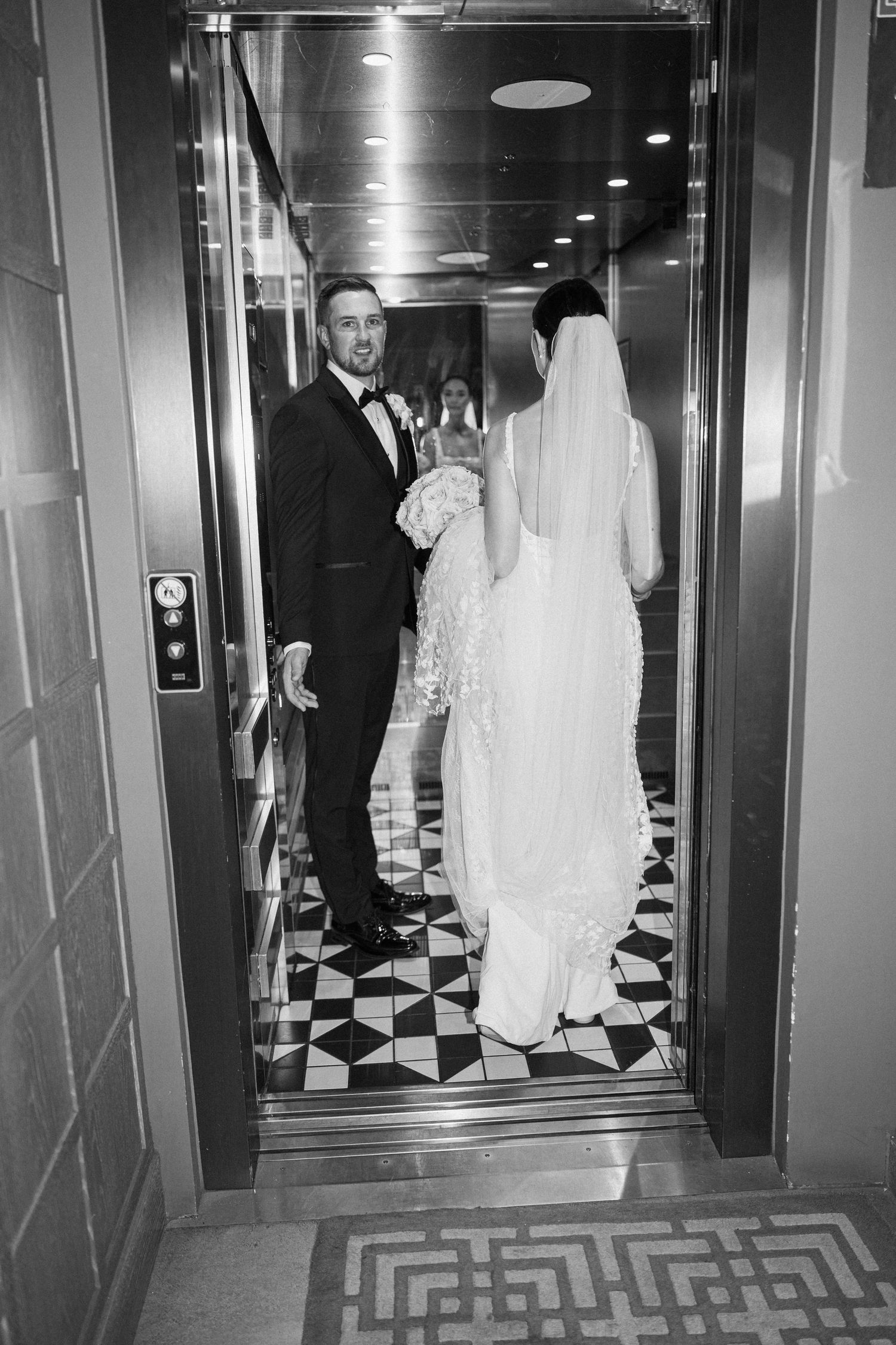 A wedding couple standing in an elevator with black and white checkered floors.