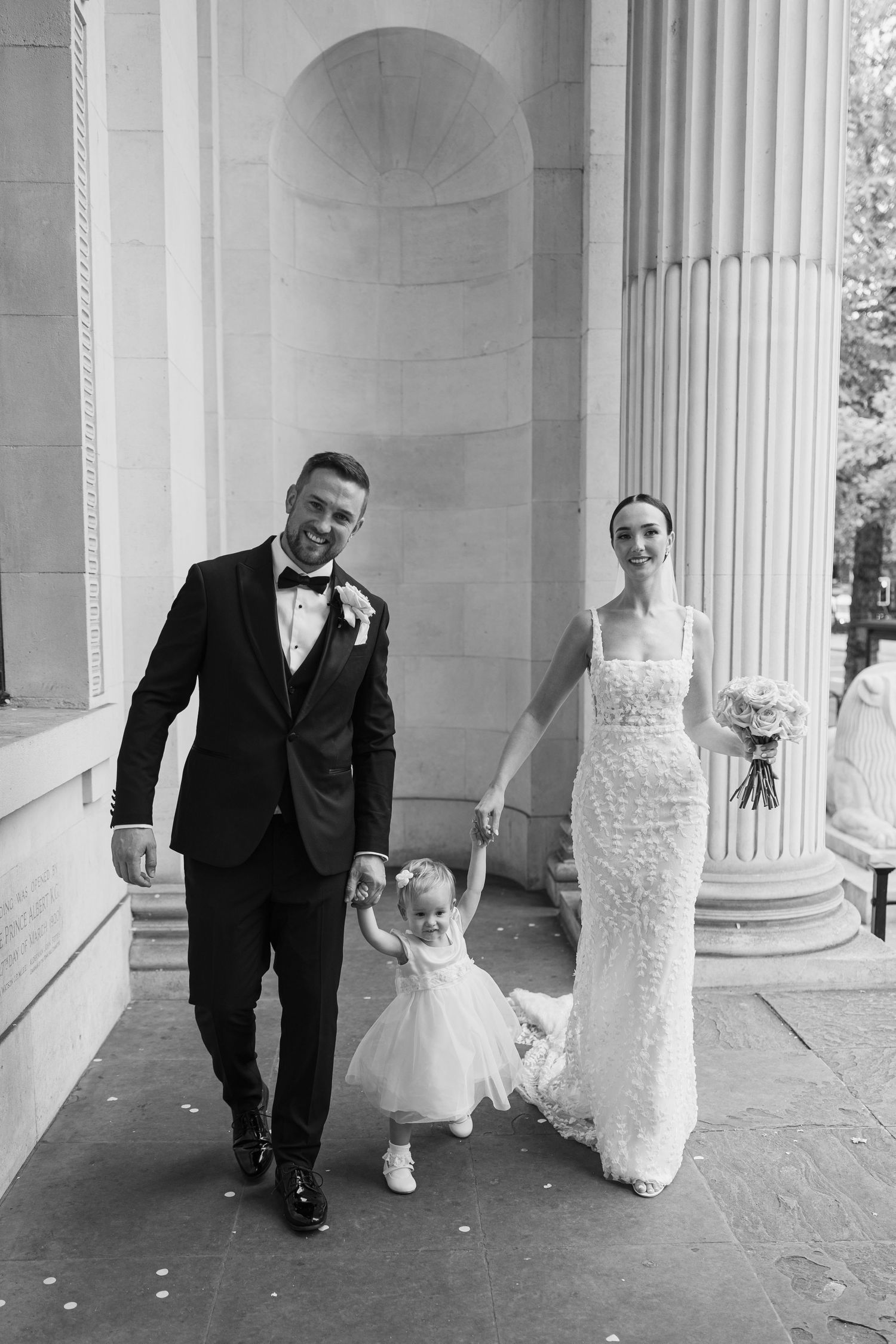 Black and white photos of a wedding couple walking through a columned gallery.