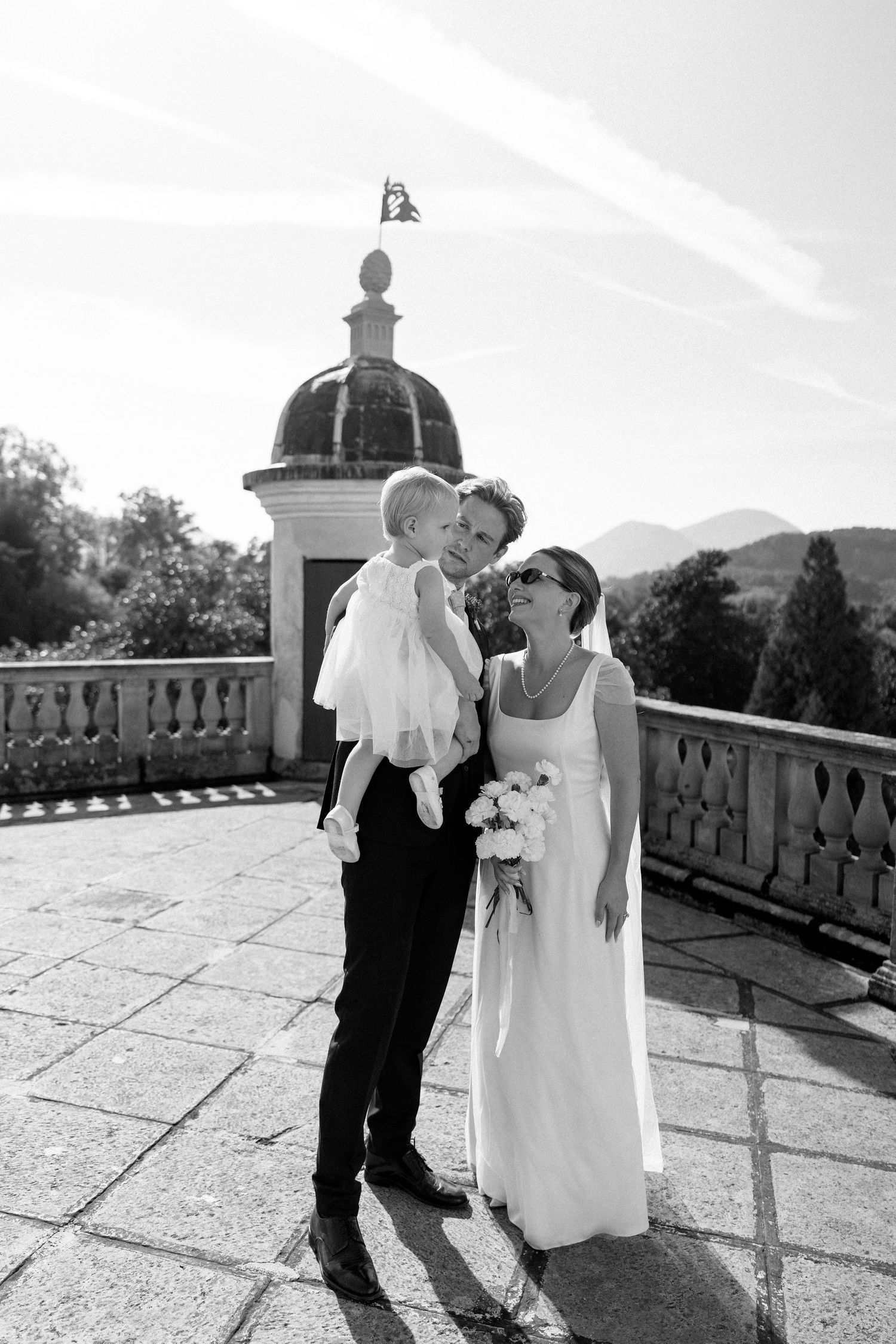 Black and white wedding portrait on castle terrace with domed architecture.