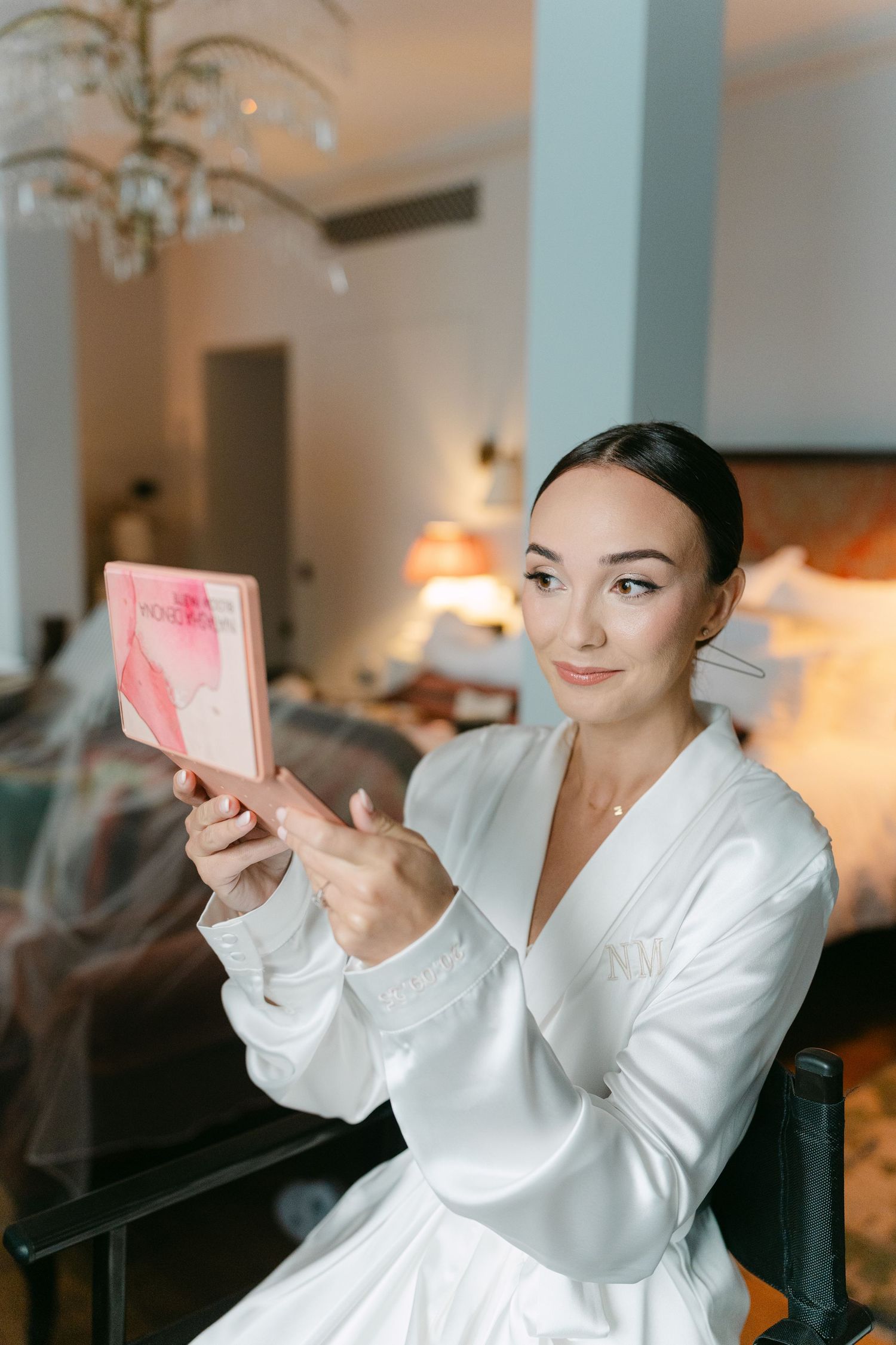 Person in white robe taking selfies in an elegant room.