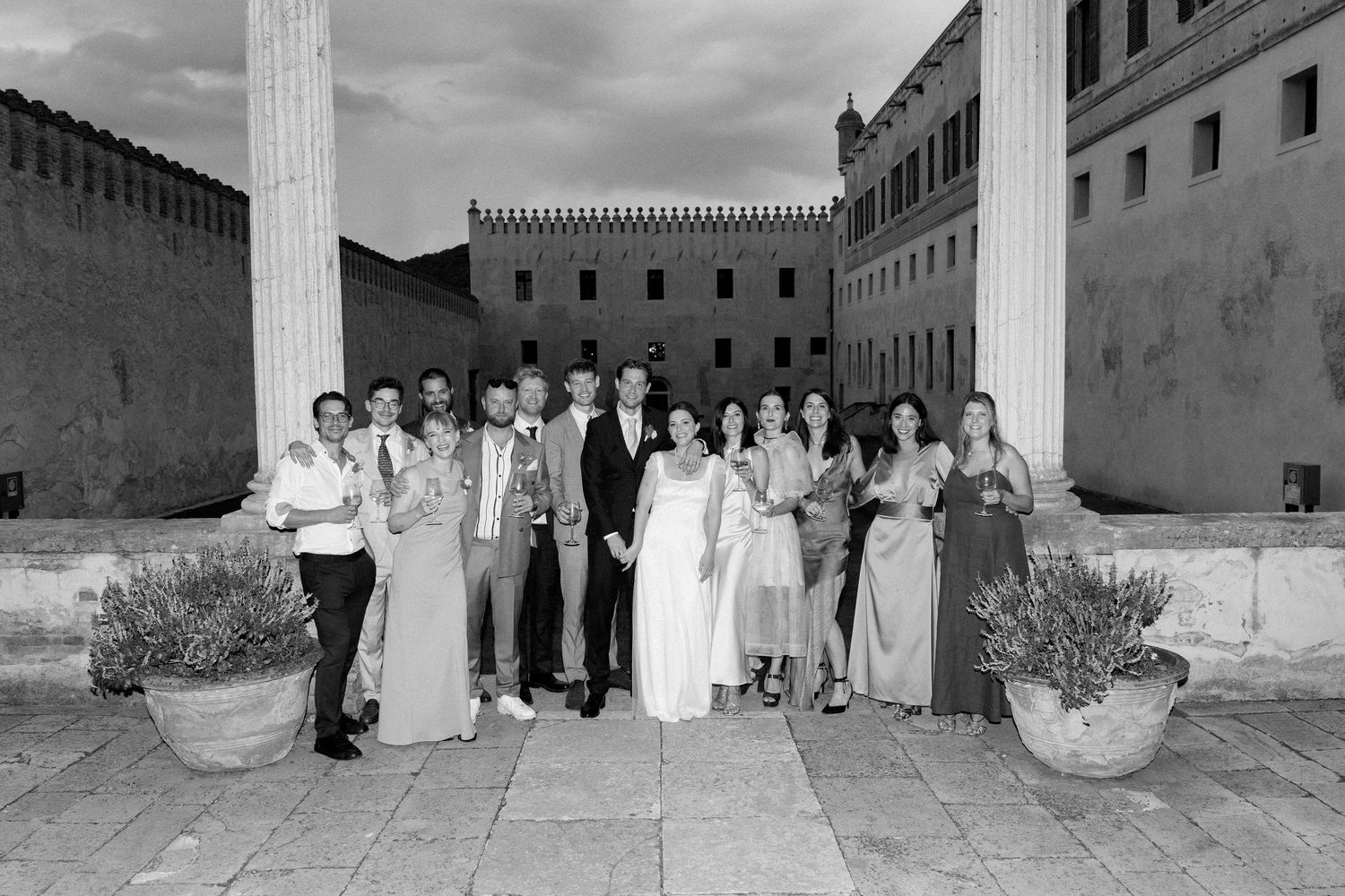 Wedding party poses in front of a classical stone building with white columns.