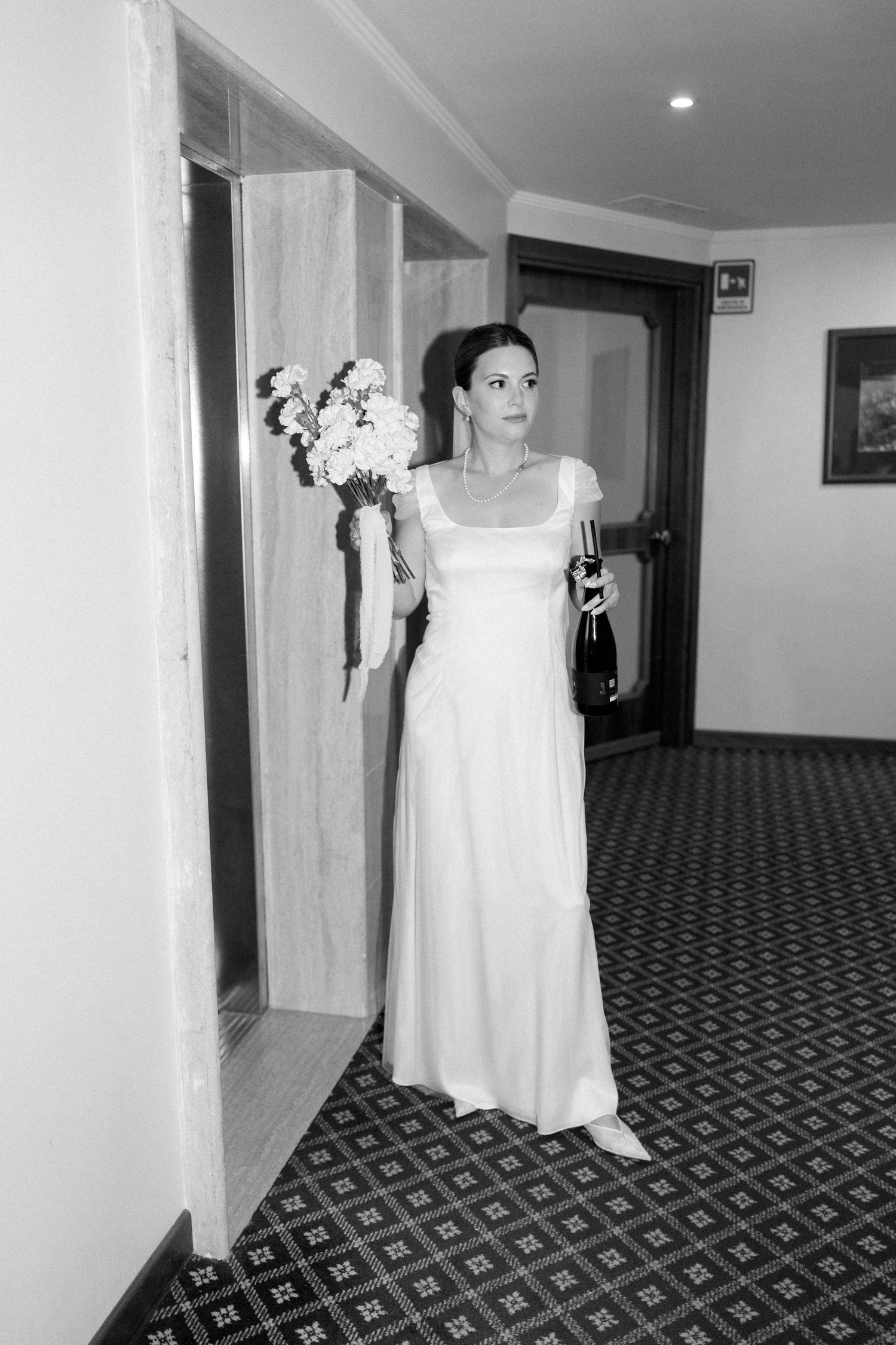 Black and white photos of someone in a white dress walking through a hotel hallway.