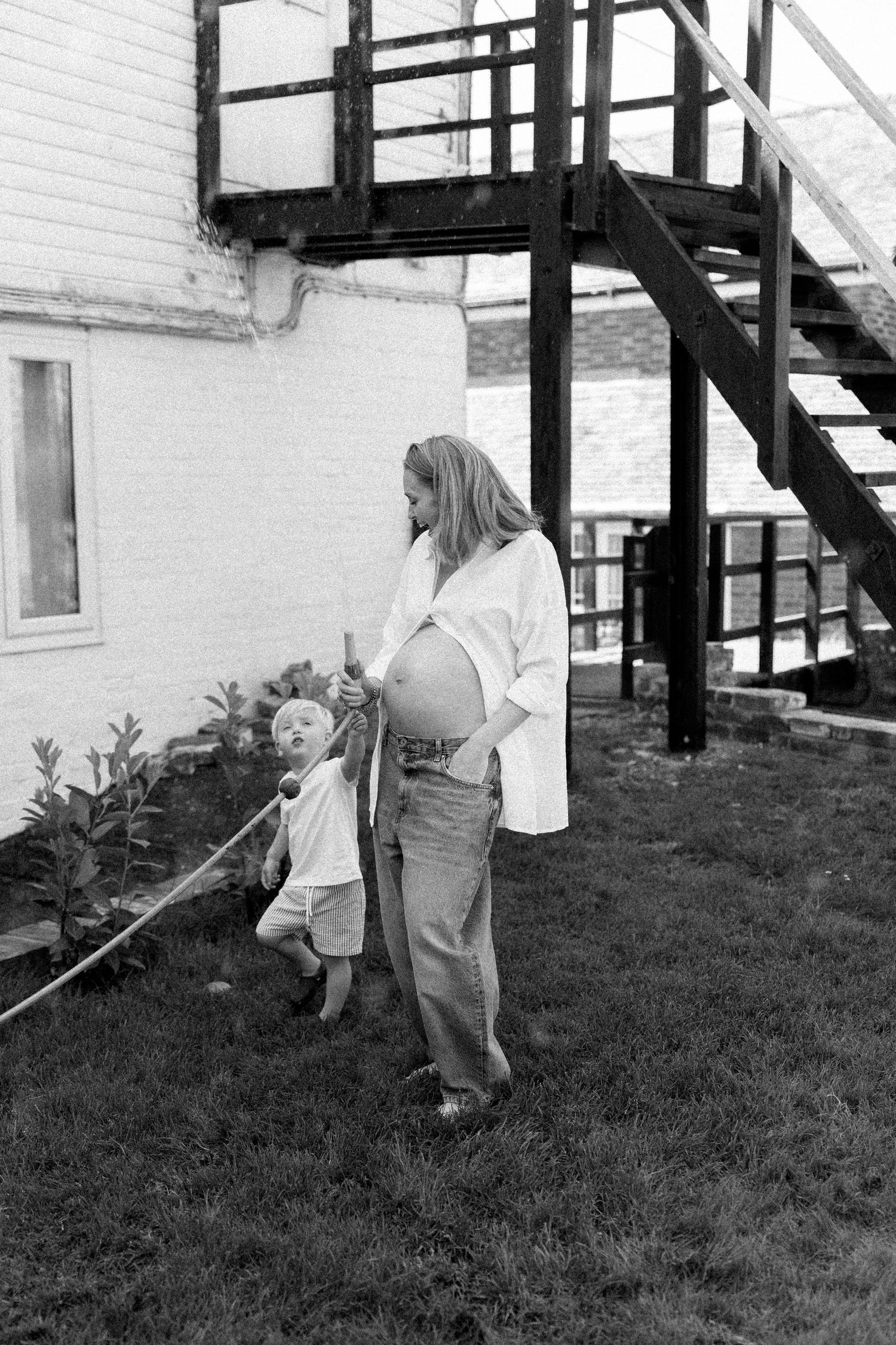 Black and white photo of people gardening in a backyard with stairs.