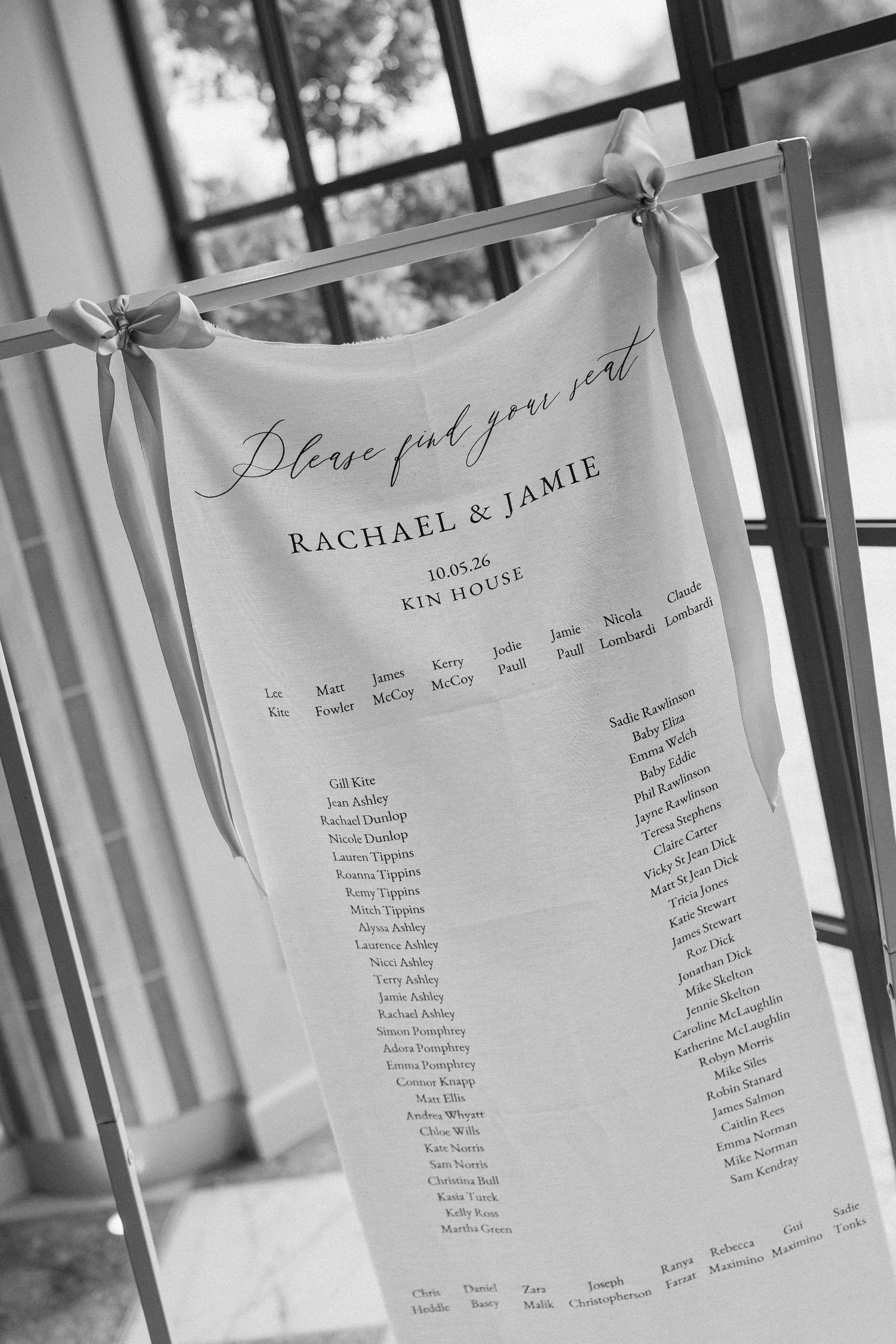 Black and white wedding seating chart for Rachael and Jamie displayed on fabric at Kin House, dated 10.01.26.