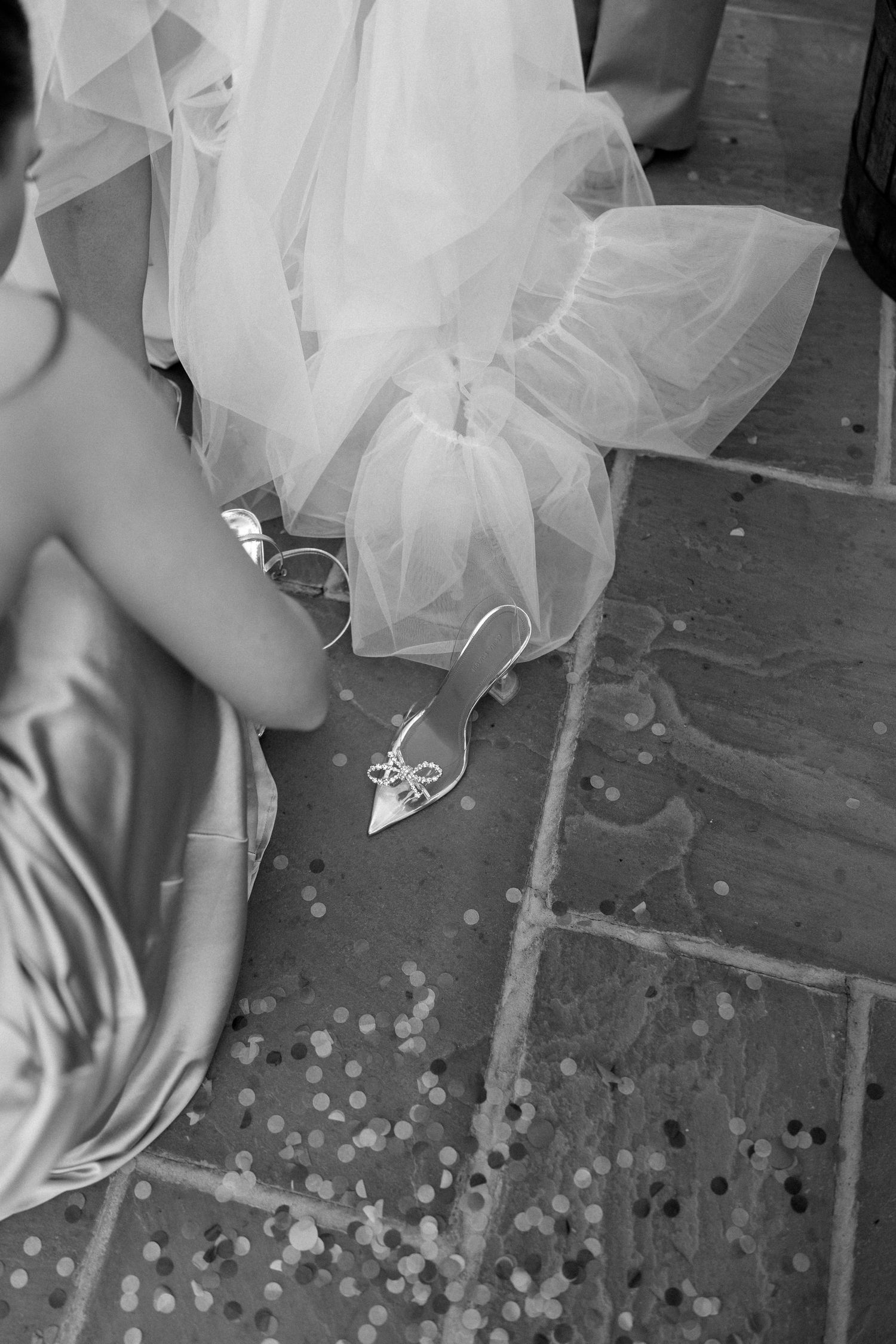 Scattered confetti dots the ground beneath flowing white tulle fabric.