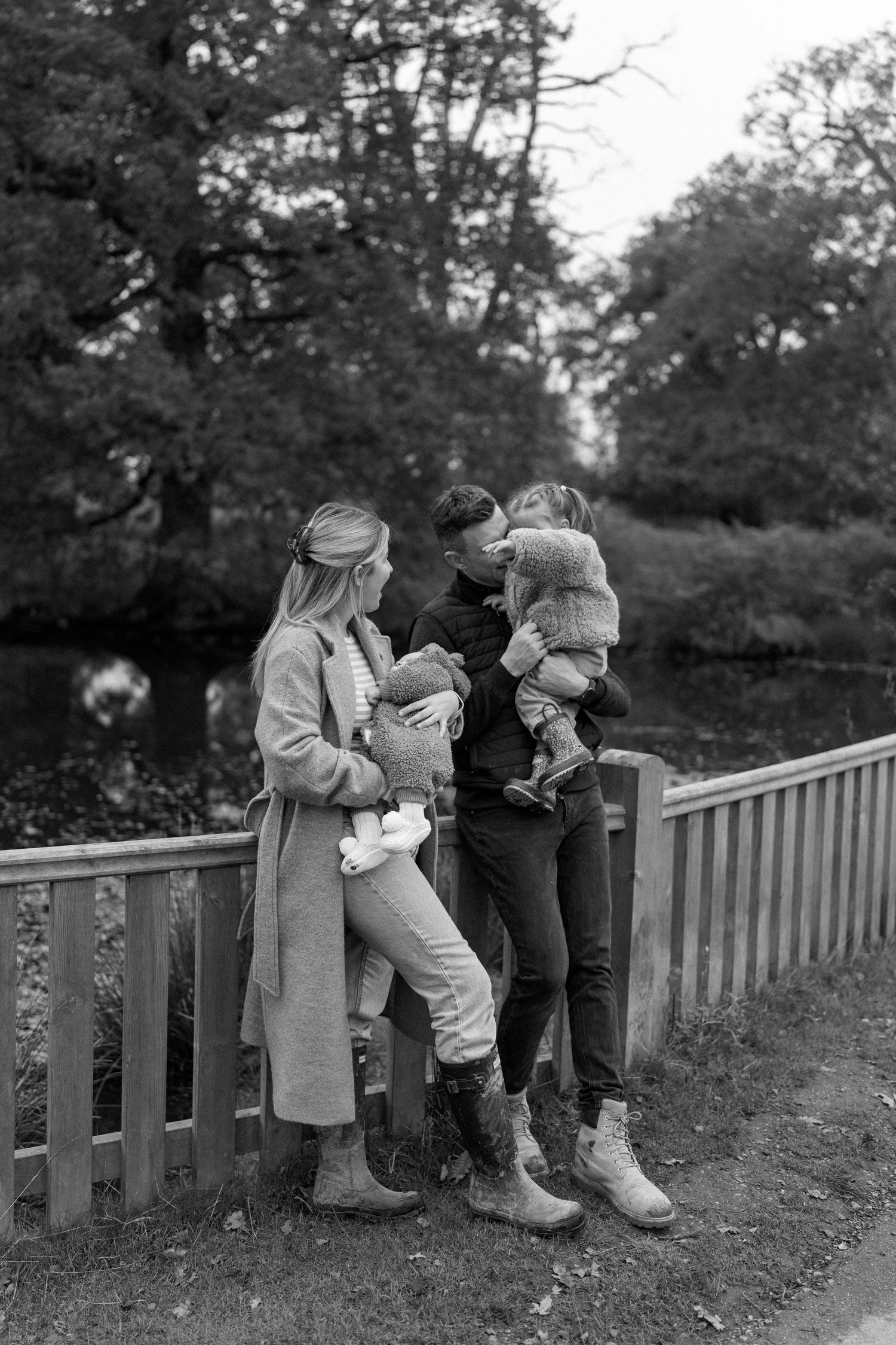 Vintage black and white photo of children sitting on a wooden fence in a row.