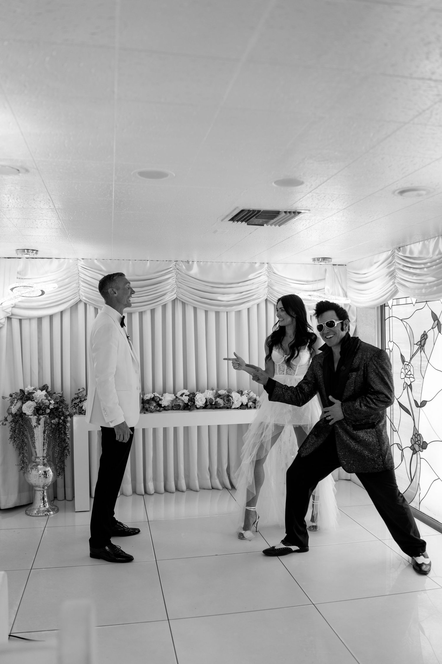 Fun candid moment during a wedding ceremony with dancing in a white-decorated chapel.