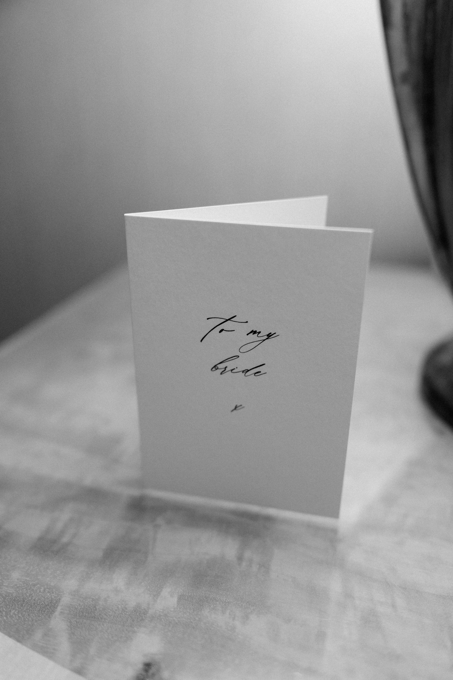 Three white place cards or name cards arranged on a light surface in a black and white photograph.