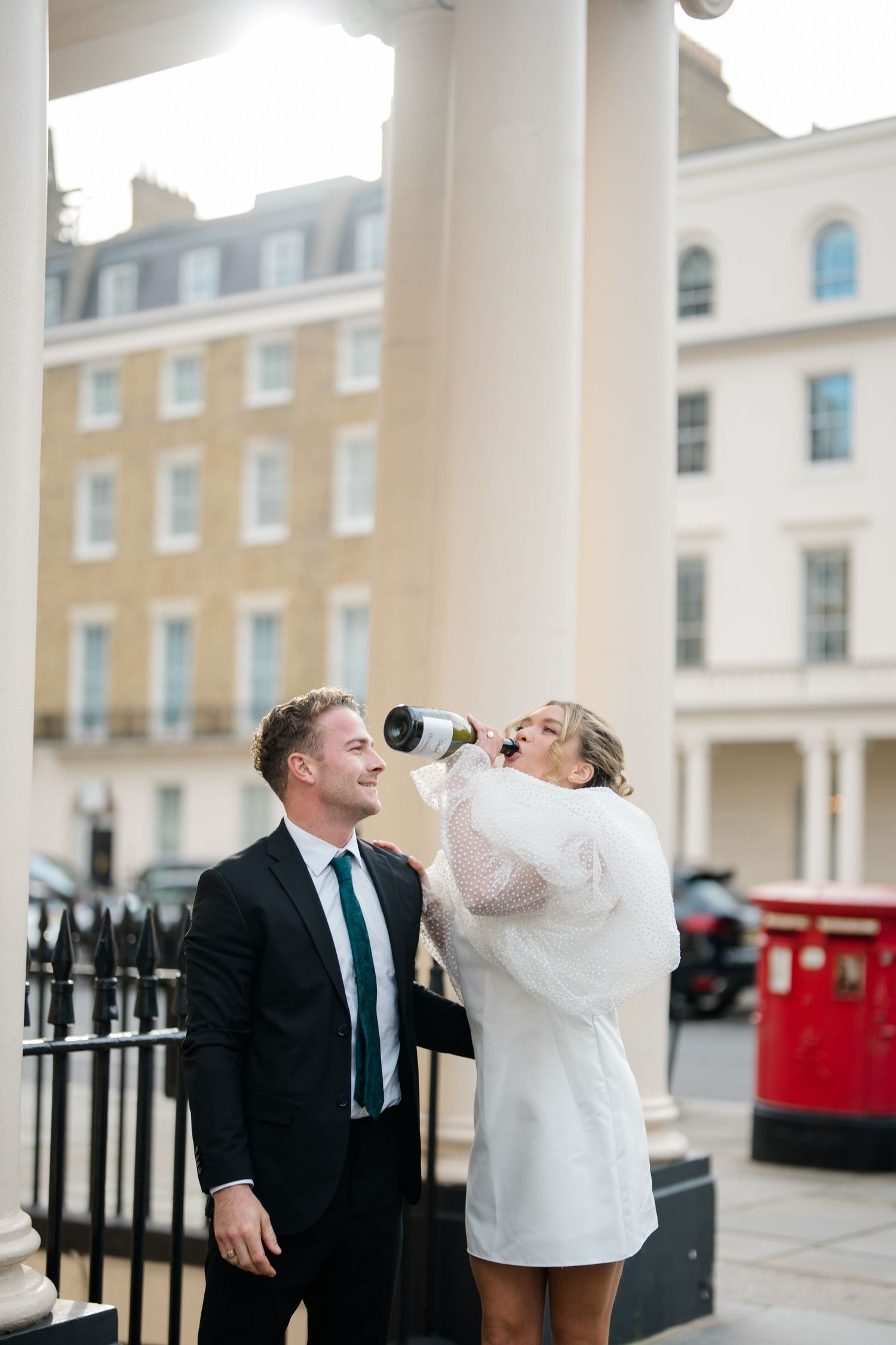 A celebratory moment captured between two people in formal wear near classic London architecture.
