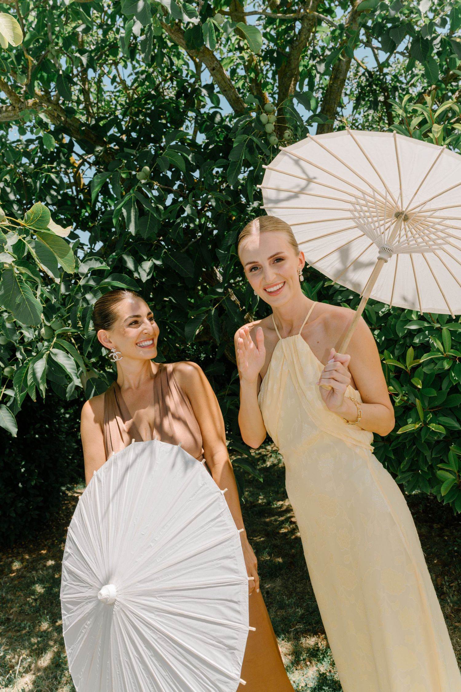 A series of photos showing people posing with white paper parasols against a leafy green backdrop in outdoor setting.