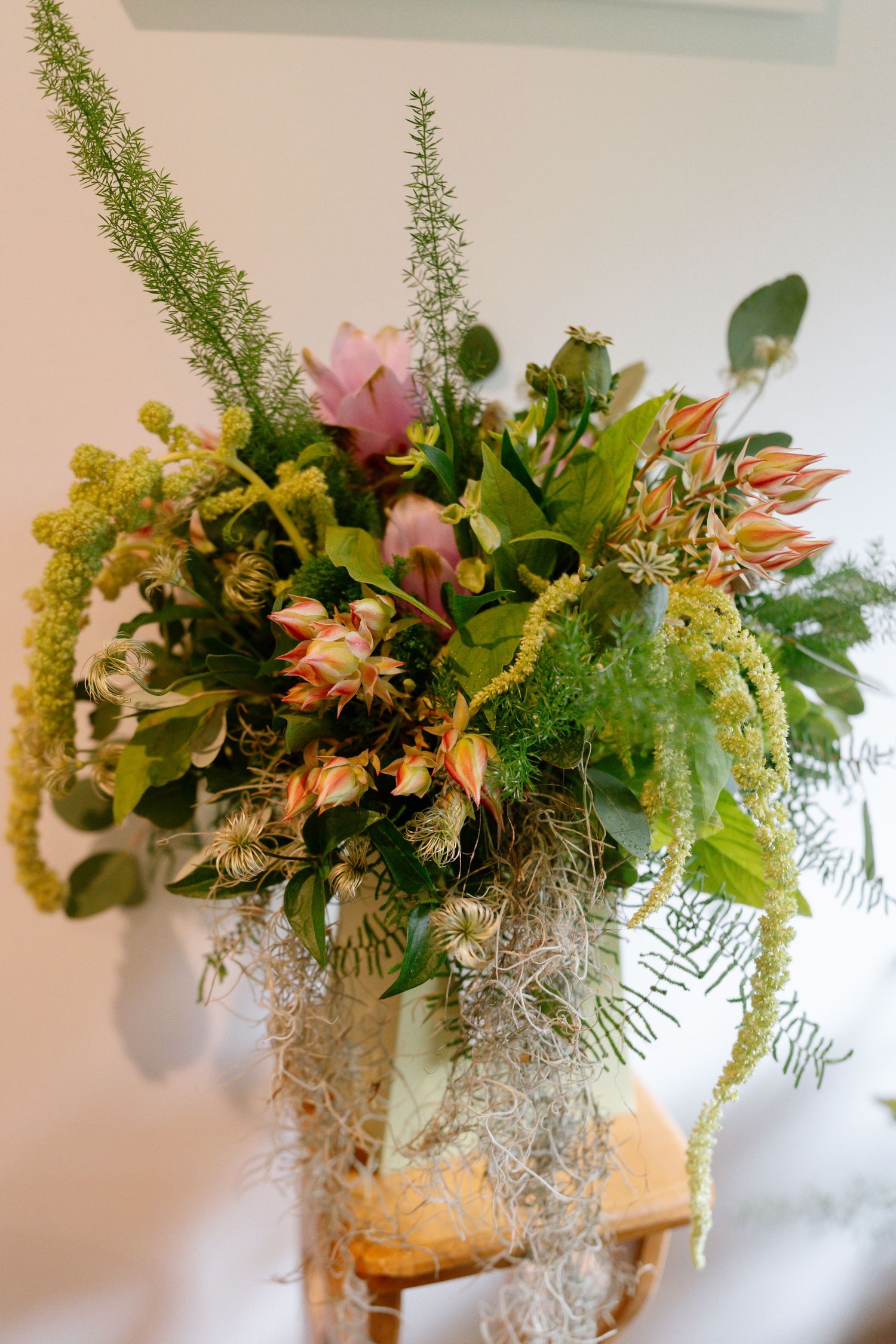 Beautiful floral arrangement with pink flowers, greenery and delicate foliage in a decorative vase.
