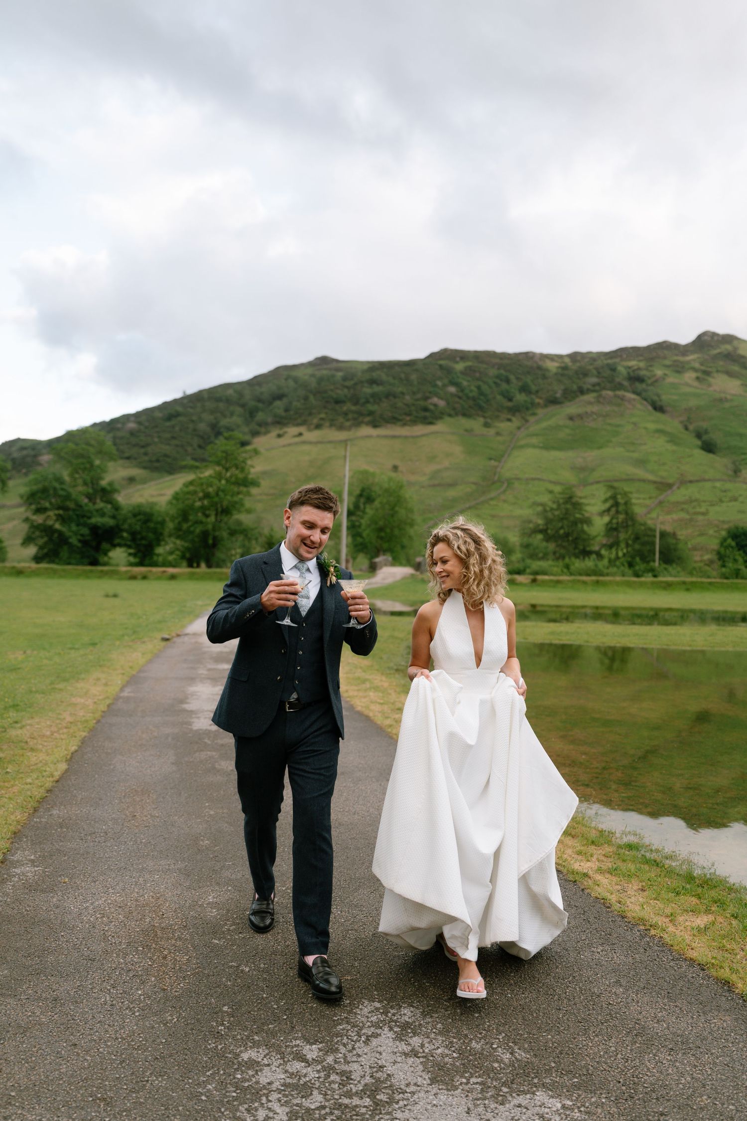 Couple walks and laughs together on path with mountains in background.