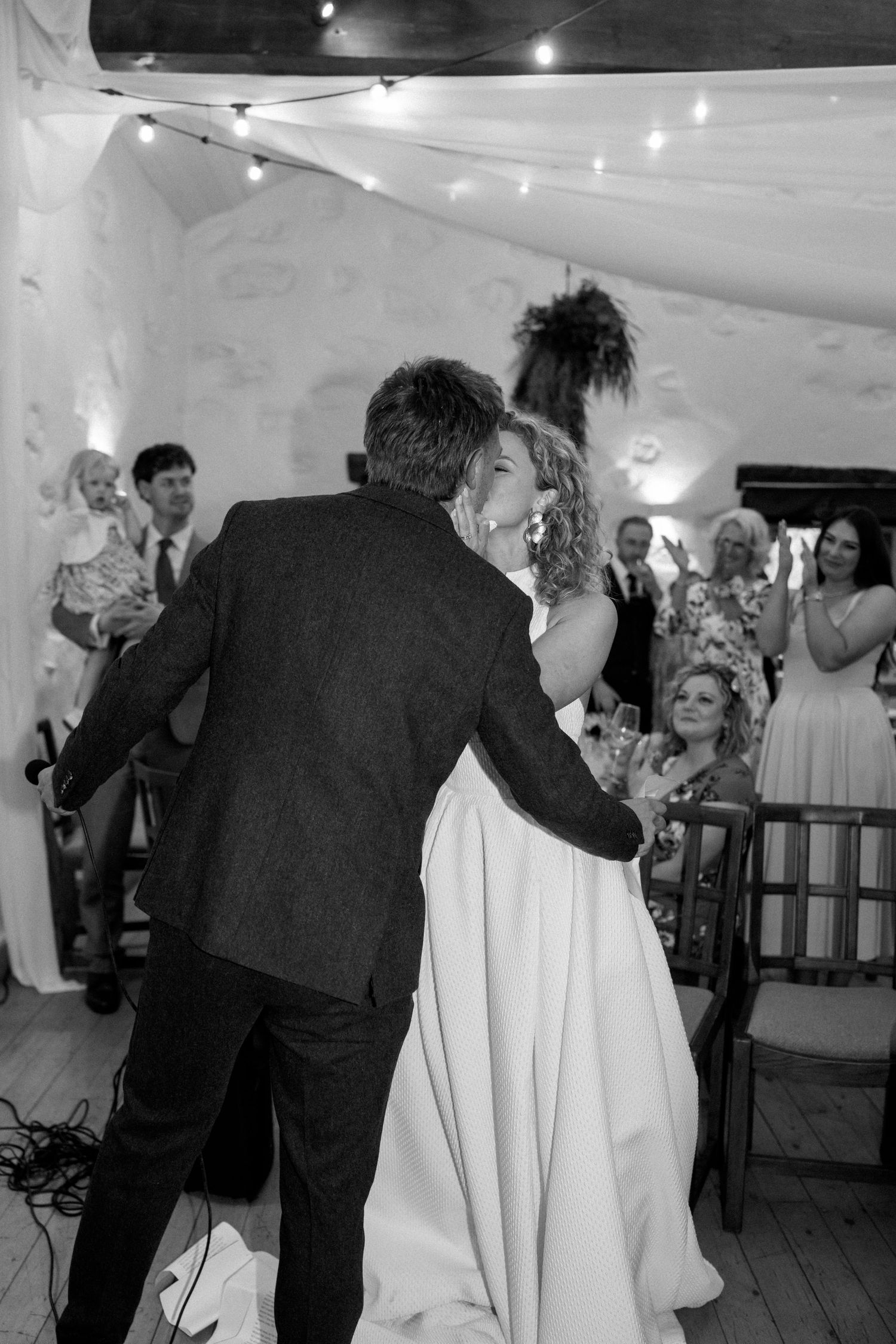 Couple sharing an intimate dance moment at their wedding reception under string lights.
