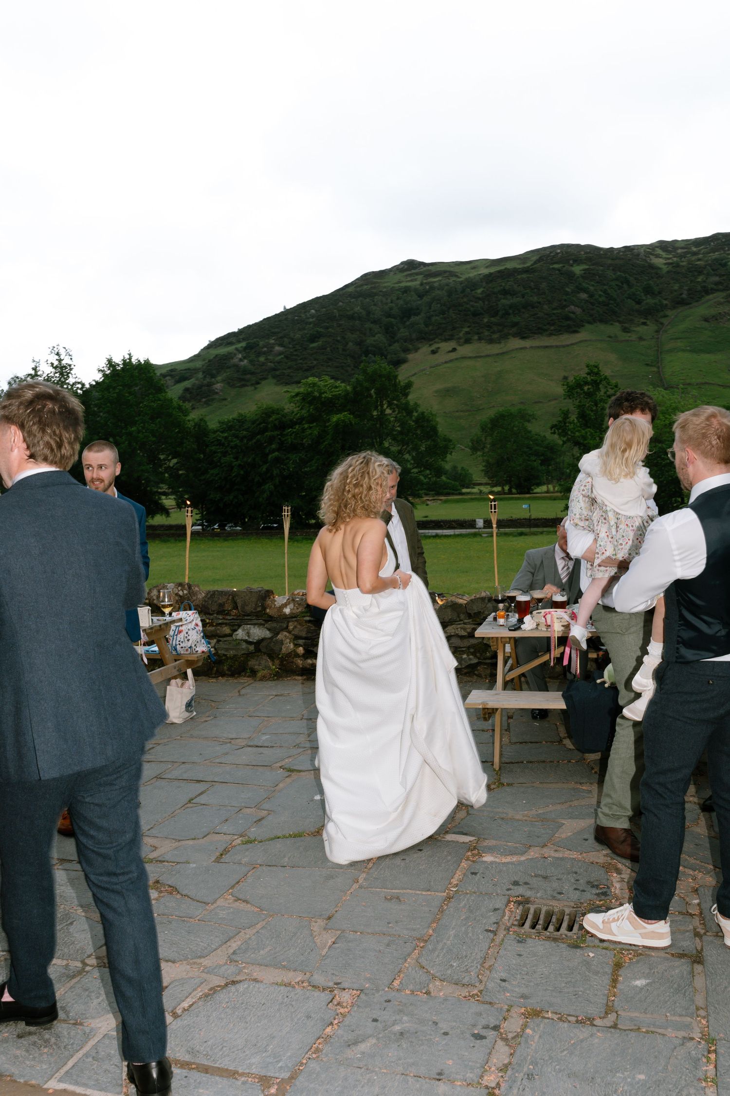 Wedding party celebrates on a stone patio with mountain scenery in the background.