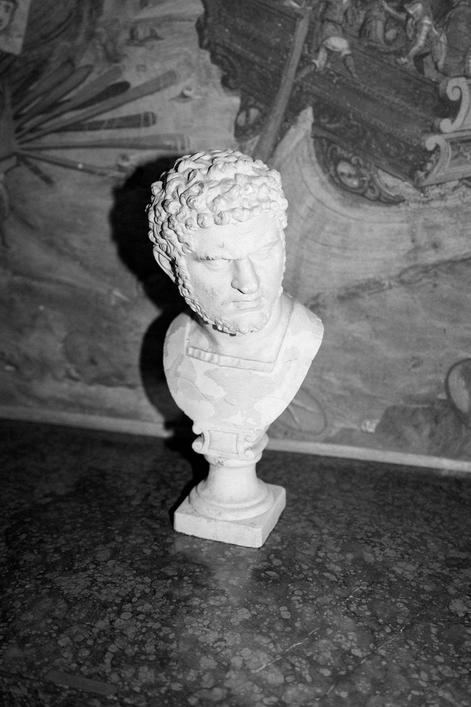 Classical white marble bust sculptures displayed on dark stone surfaces in a dimly lit setting.