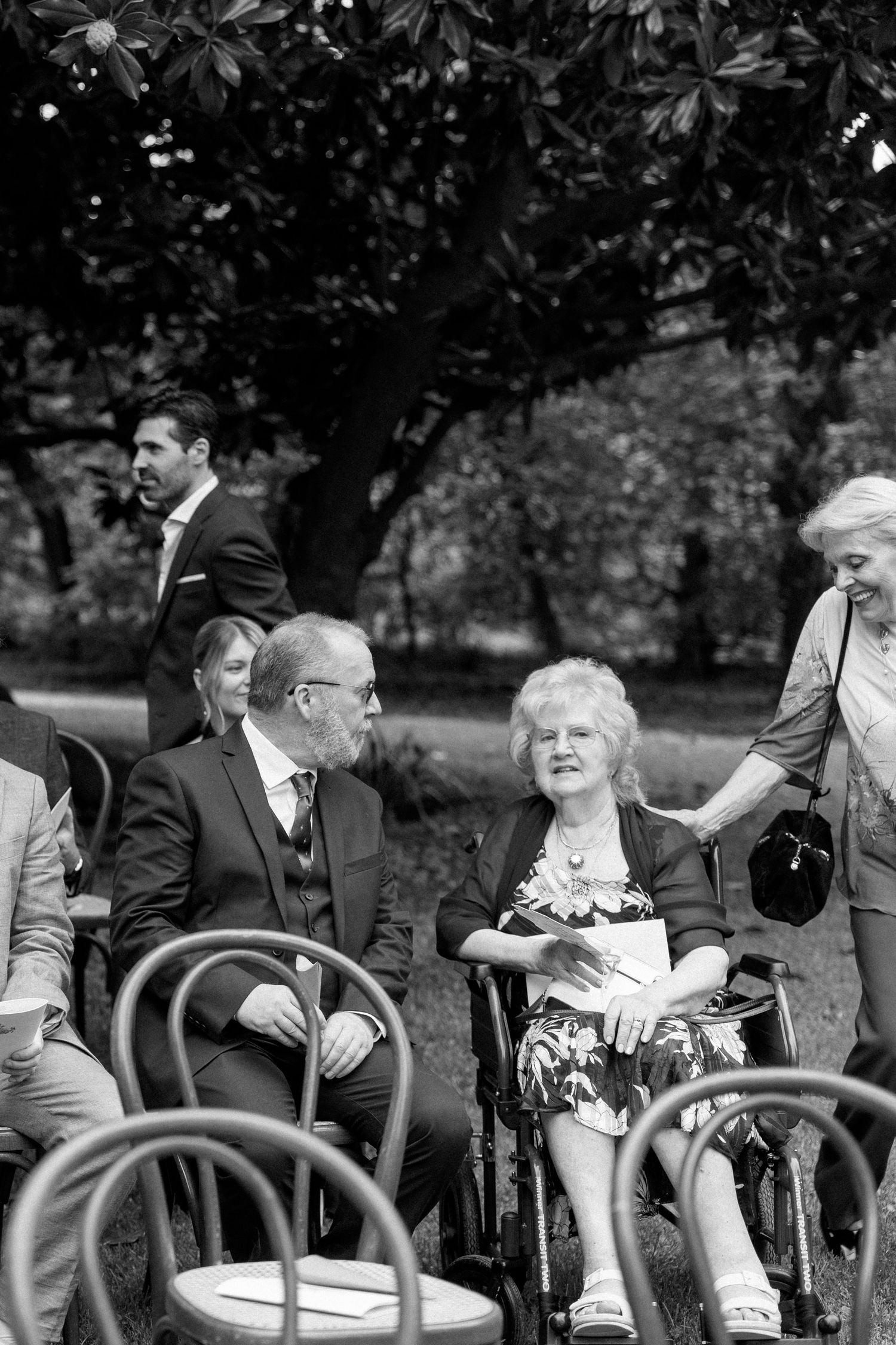 Guests seated in outdoor chairs enjoying conversation at an elegant event.