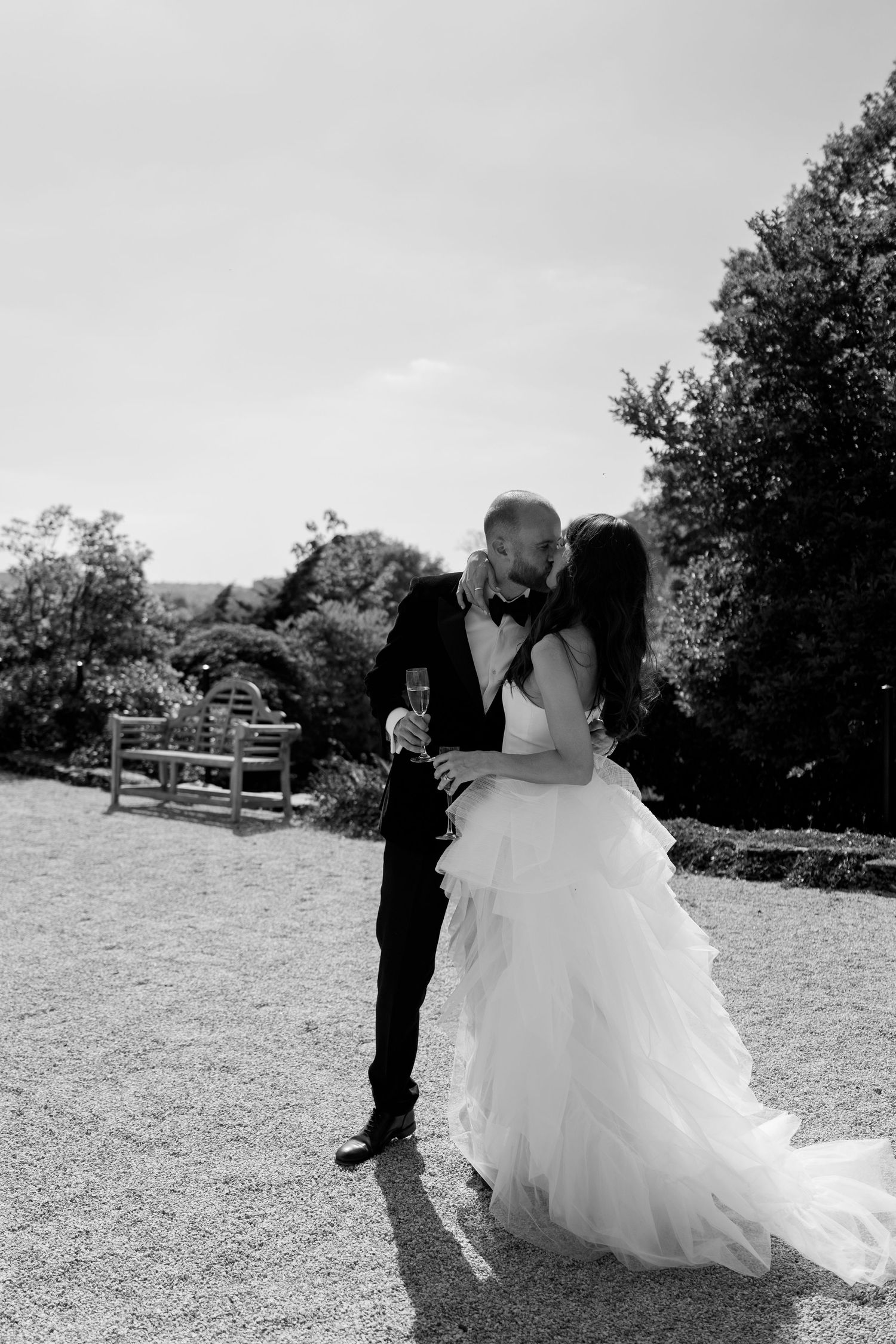 A romantic wedding moment captured in black and white on an outdoor lawn.