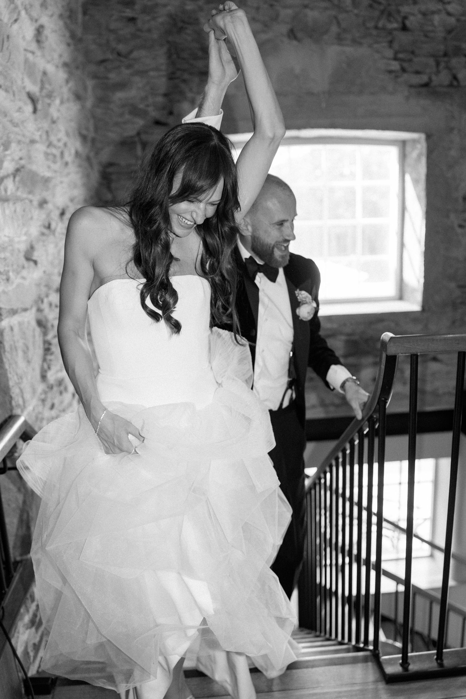 Wedding celebration on stone staircase with flowing white dress.