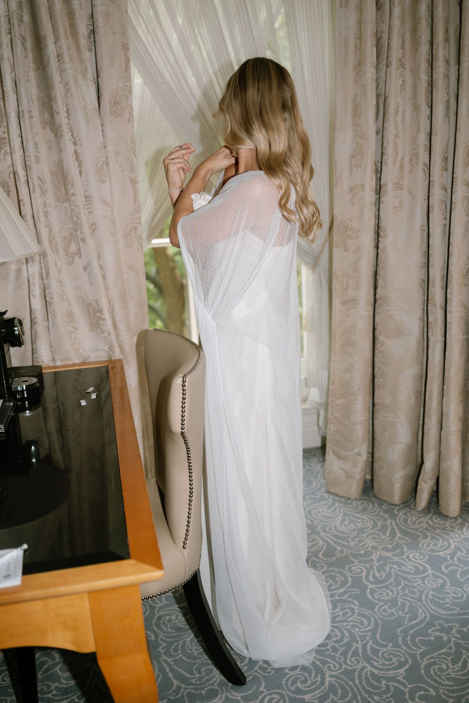 Wedding dress fitting moment captured in elegant dressing room with natural light.