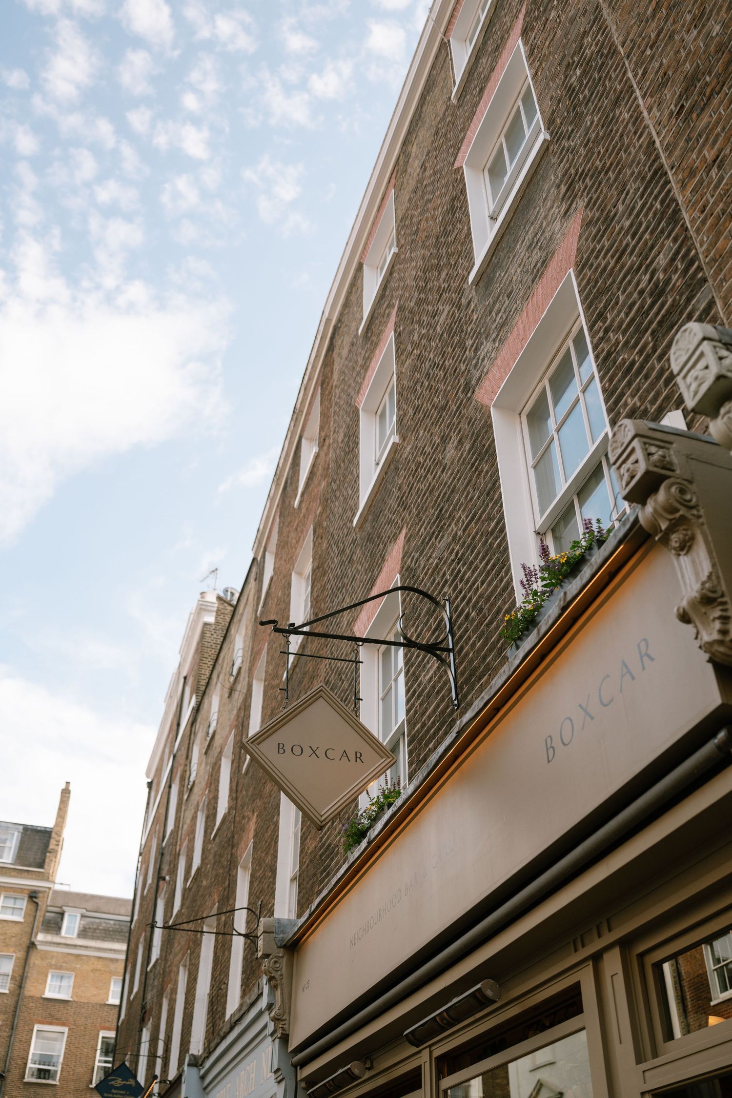Exterior view of classic London brick buildings with white trim and windows against blue sky.