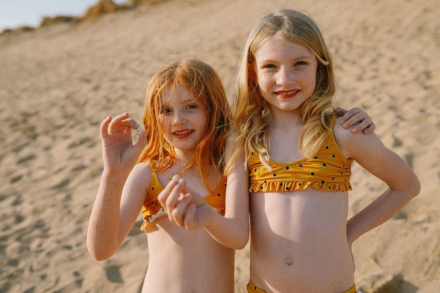 Children playing together on a sandy beach at sunset.
